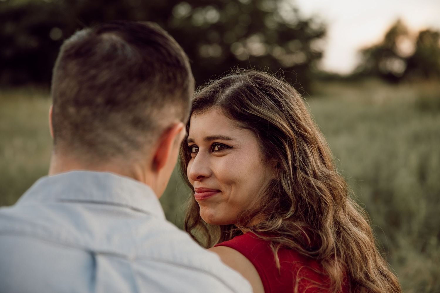 A romantic couple embraces in a field during an overcast evening photoshoot.