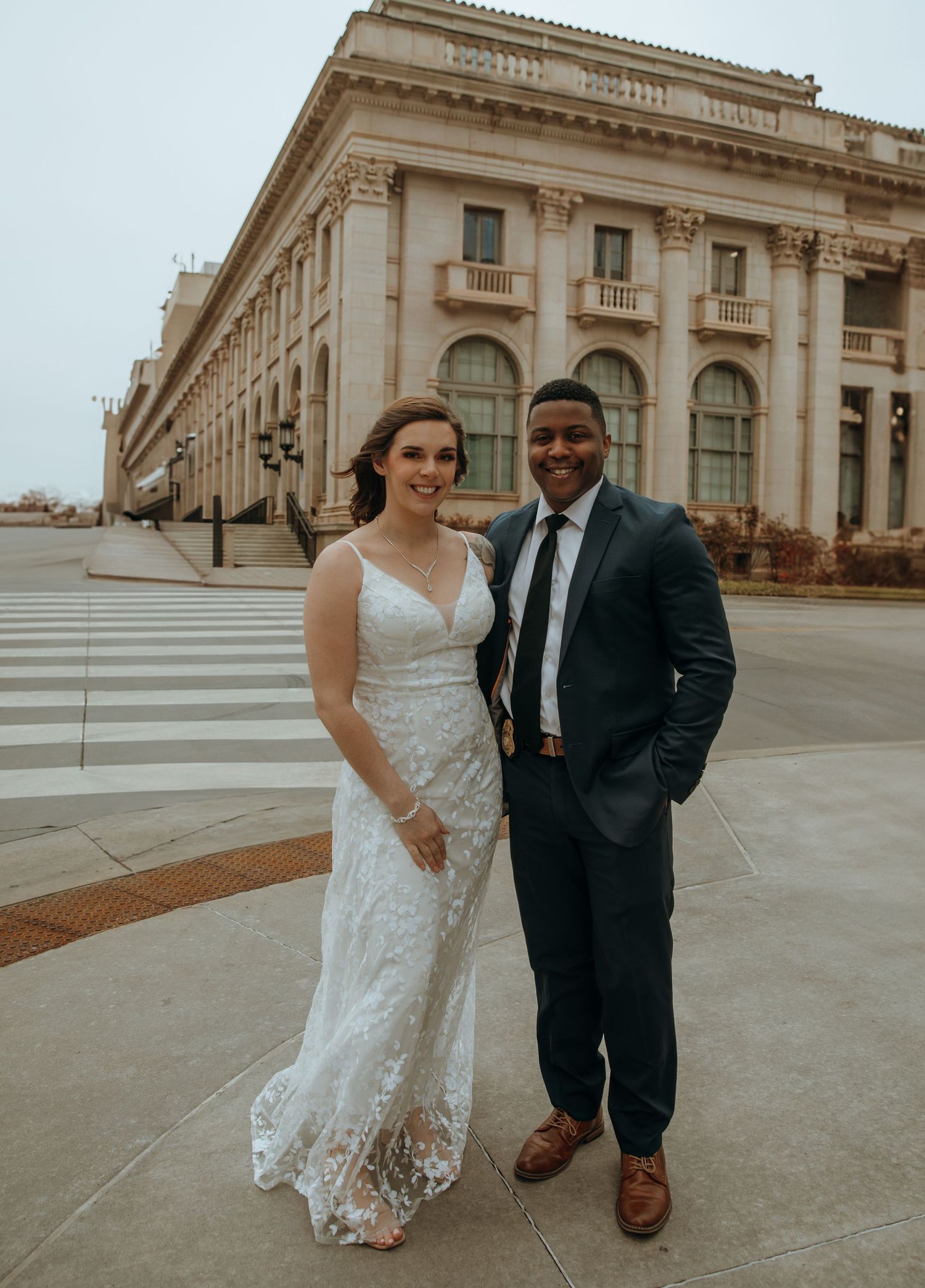 Wedding couple poses outside a grand classical building with stone columns and steps.