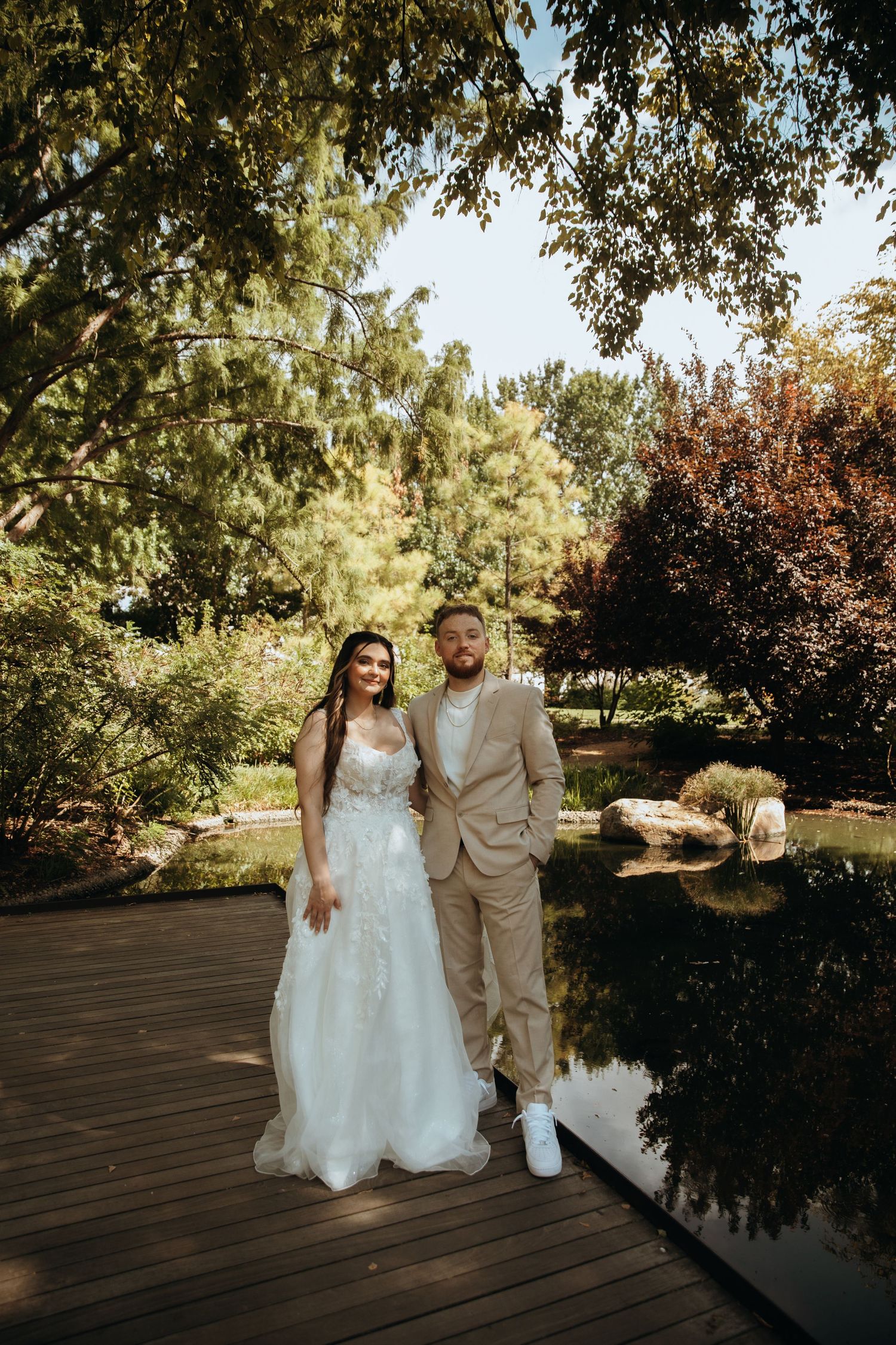 Bride and groom portrait session on outdoor wooden deck with natural landscaping.