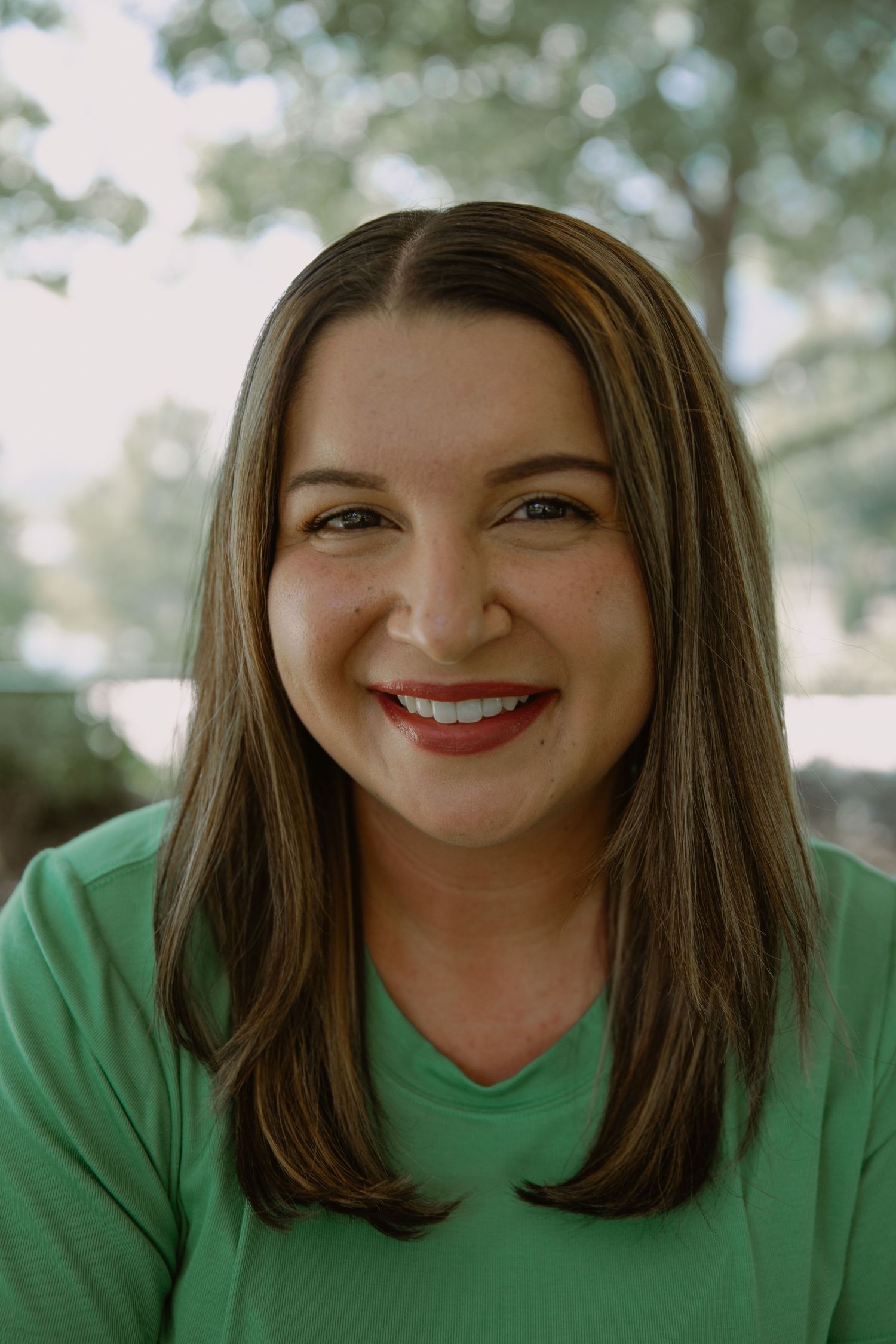 Portrait series showing warm smiles and expressions while wearing a green shirt outdoors.