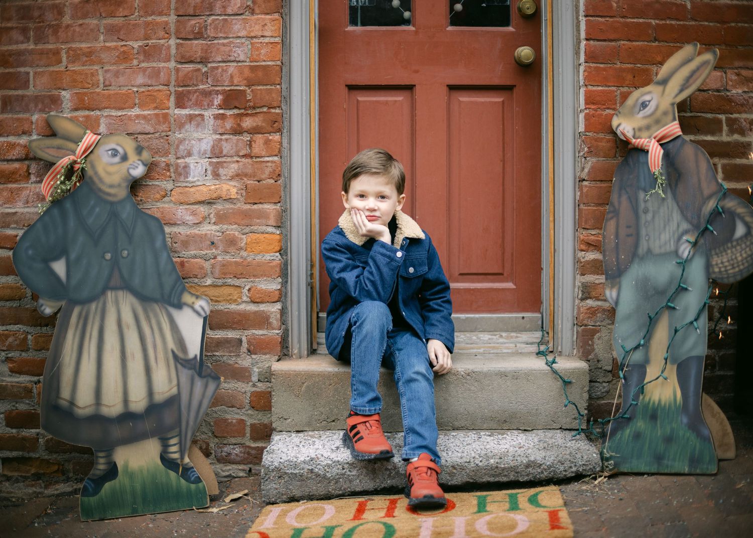 A child in Reeder's Alley in Helena at Christmas posing with antique toys and props against brick walls.
