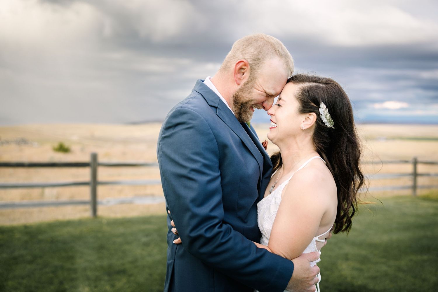 An intimate wedding portrait with dramatic cloudy sky in the background.