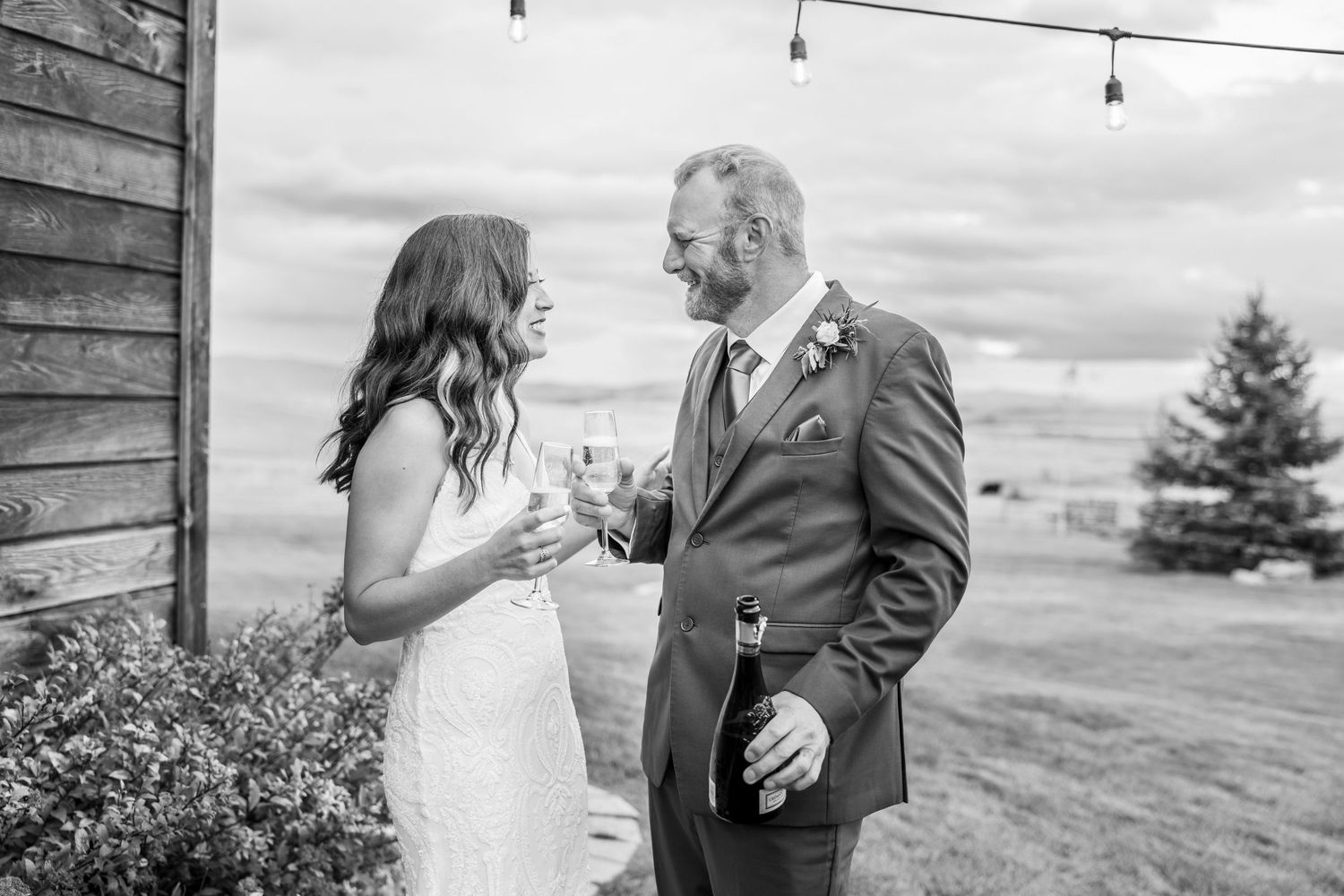 A romantic outdoor wedding photoshoot in black and white featuring a couple in formal attire on a scenic hillside.
