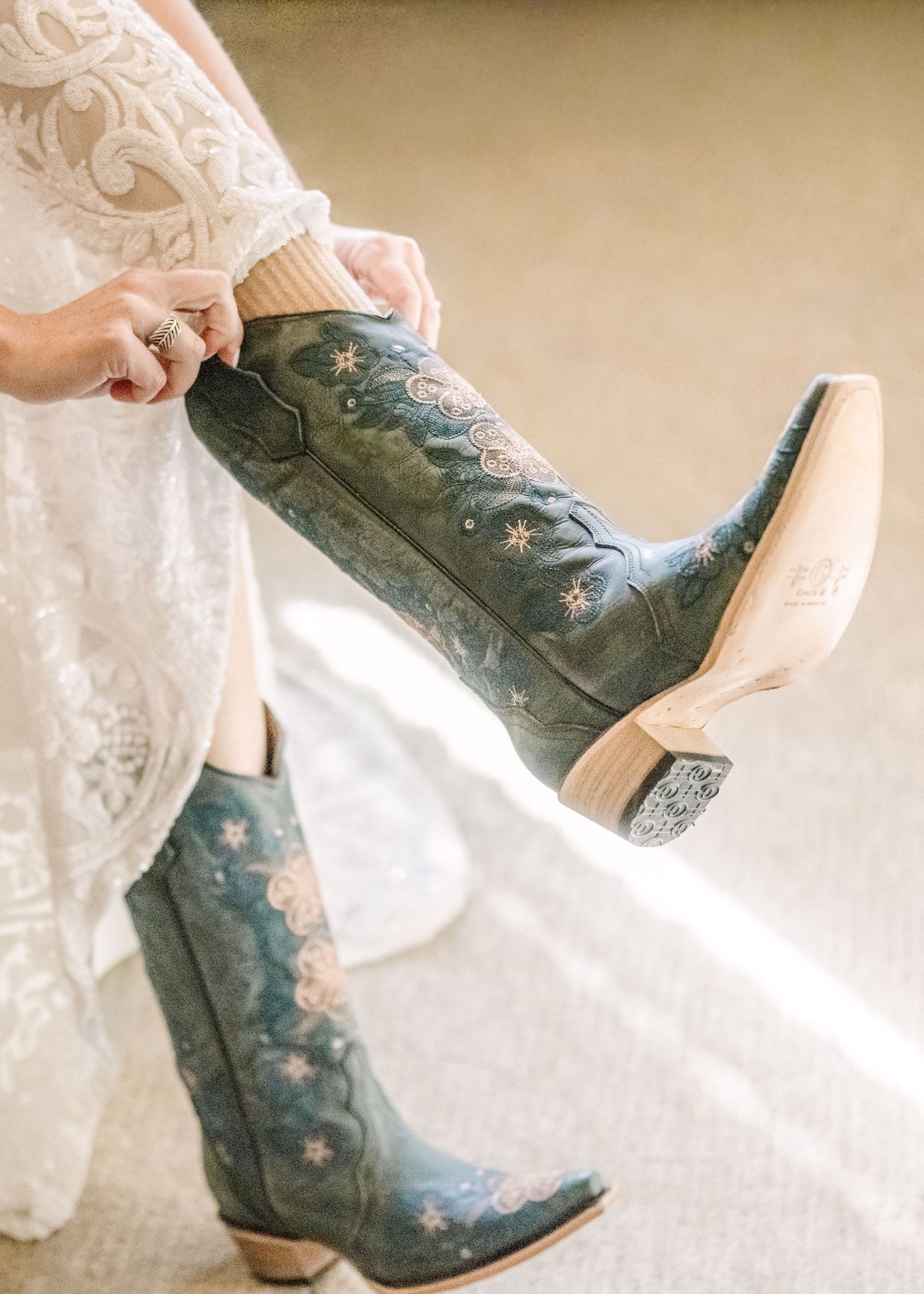 A sequence showing decorative blue cowboy boots with floral embroidery being put on with a white lace dress.