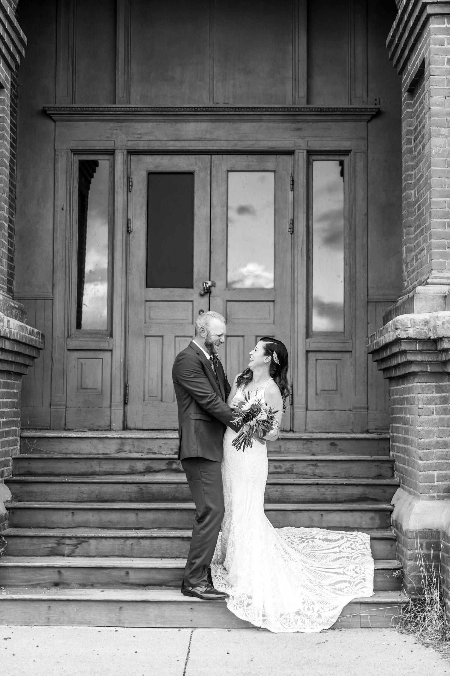 Black and white wedding photo series showing couple in romantic poses on a brick building porch.