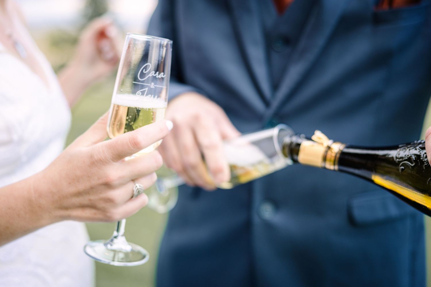 A group of people in formal attire hold champagne glasses during an elegant outdoor celebration.