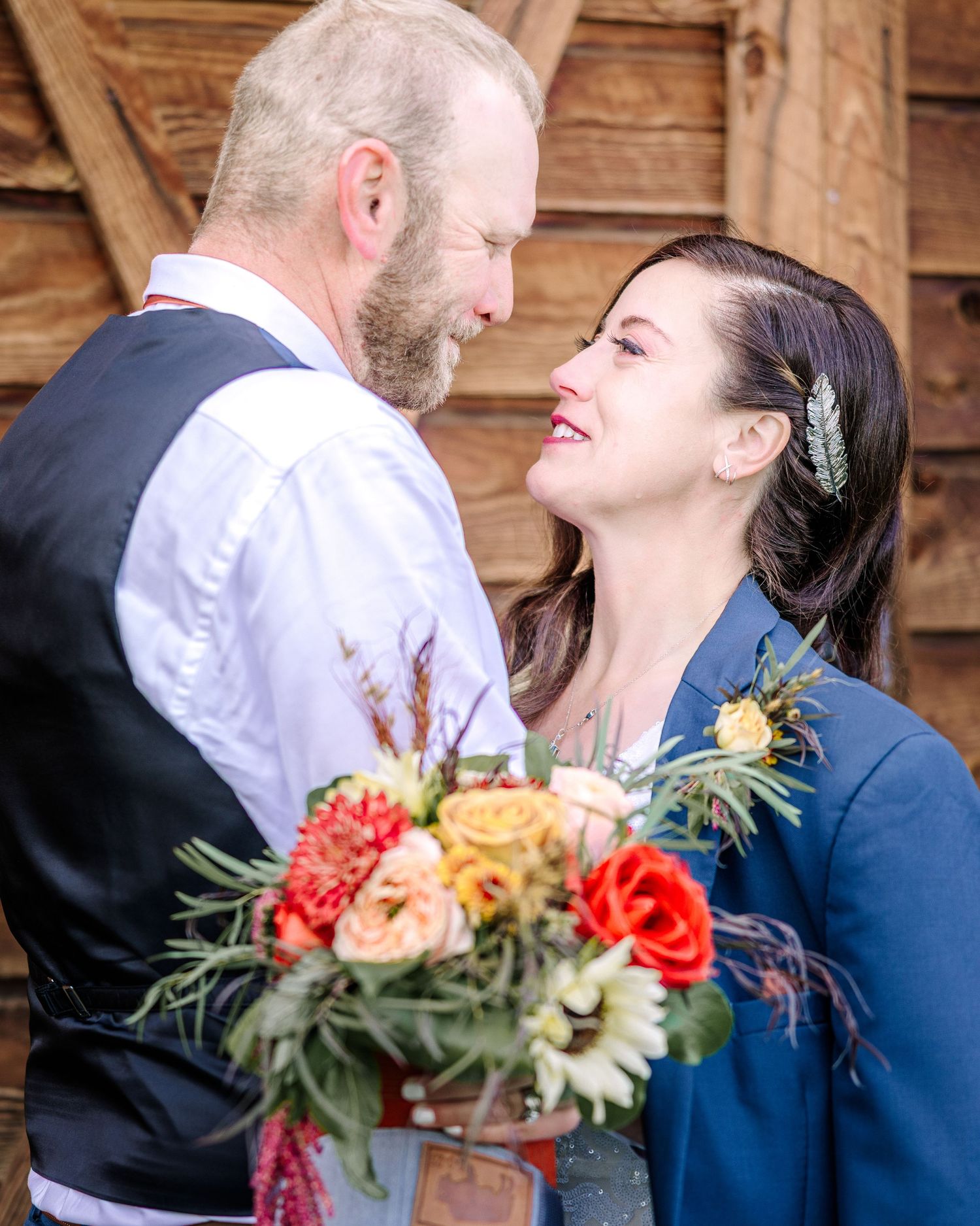 A couple shares an intimate moment at their wedding with a vibrant orange and peach floral bouquet.