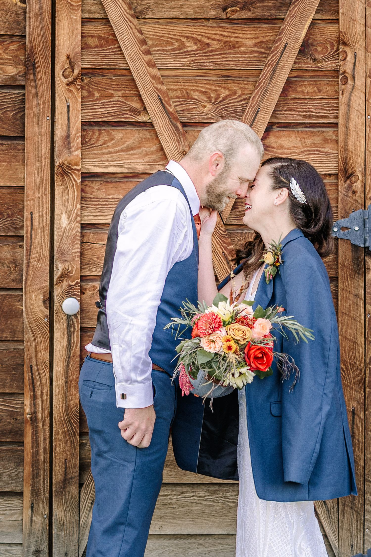A romantic wedding couple shares three sweet kisses against a rustic wooden barn wall backdrop.