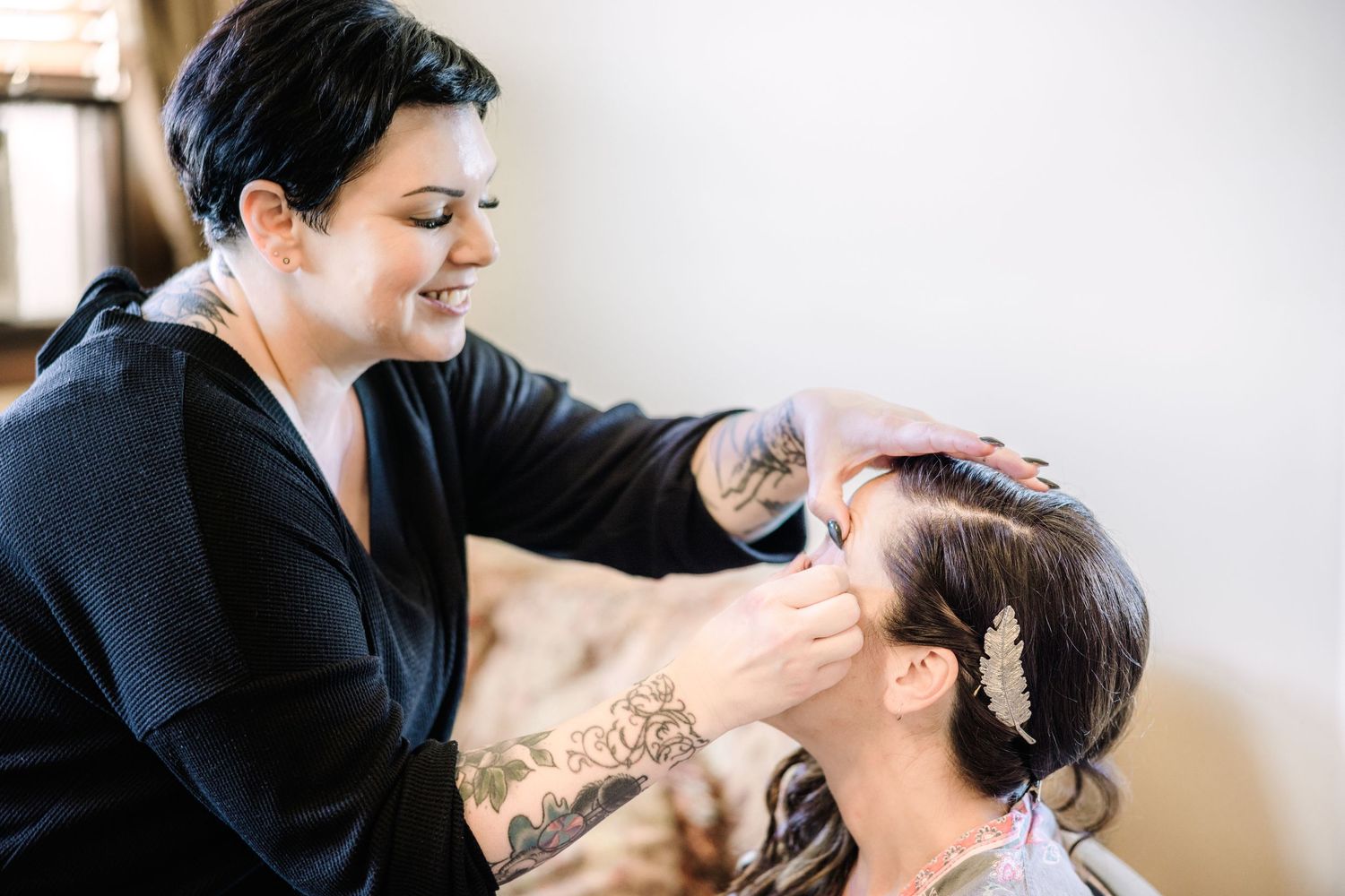 Professional makeup artist applies cosmetics to client during bridal preparation session.