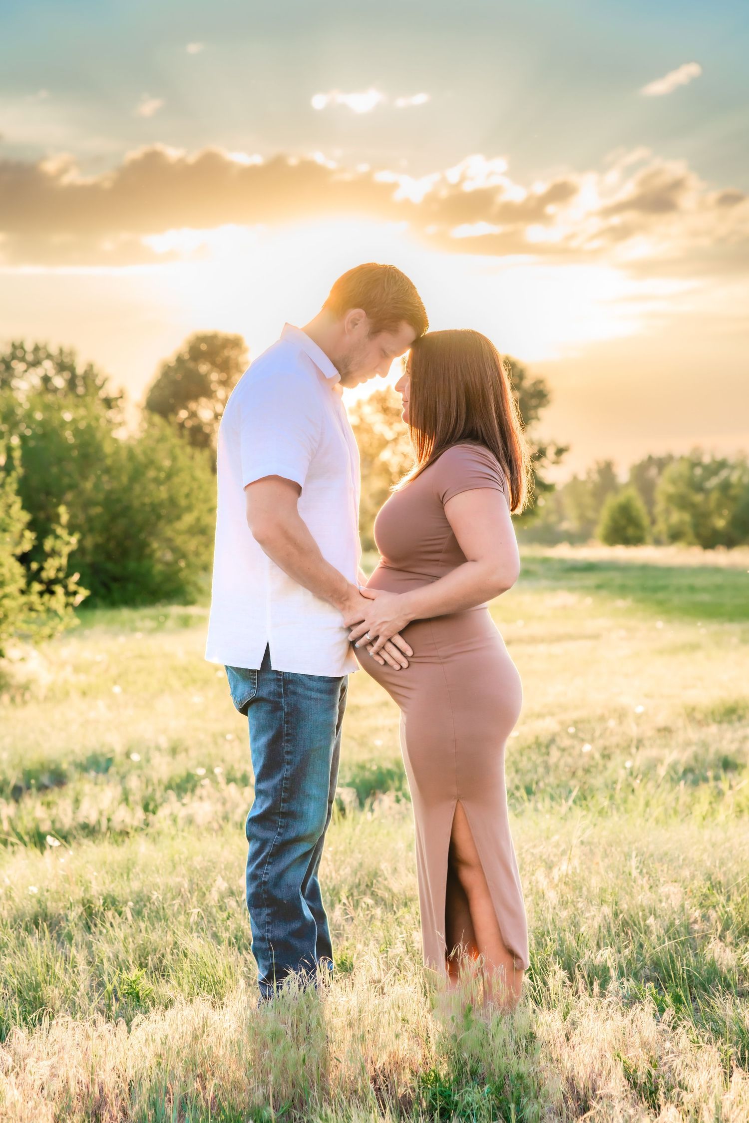 A maternity photo of a couple at sunset in a golden field. A photo by Kelsea Laine Photography.