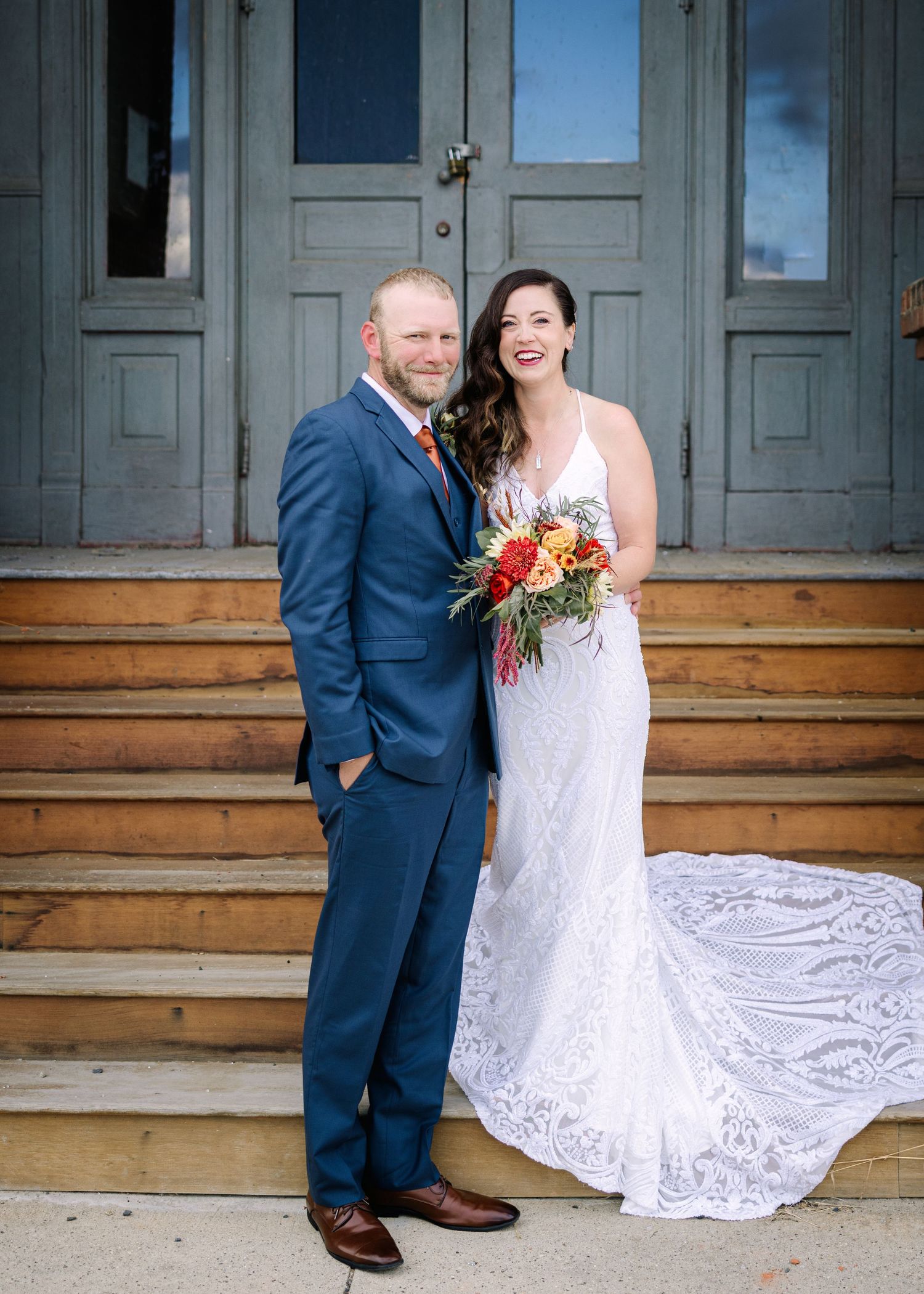 A couple in wedding attire sits on wooden steps outside a historic building, showing a series of candid poses.
