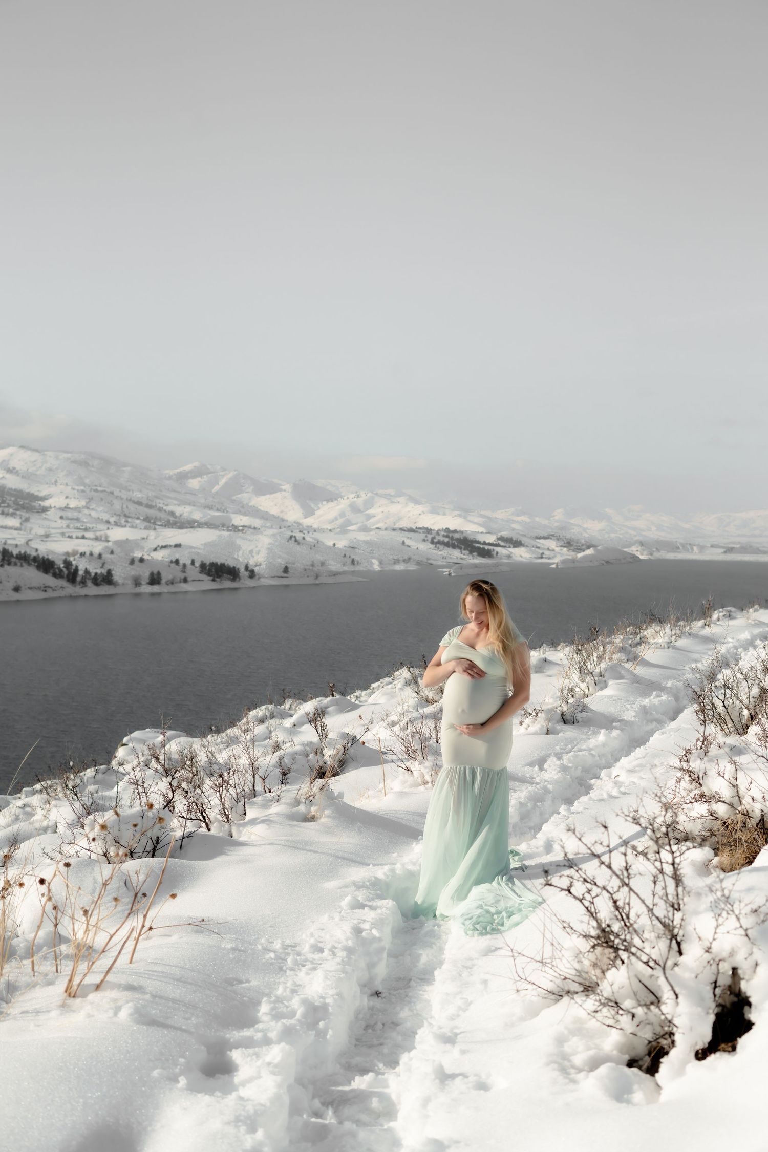 A winter landscape panorama shows a figure in a light blue dress against snowy mountains and a serene lake backdrop.