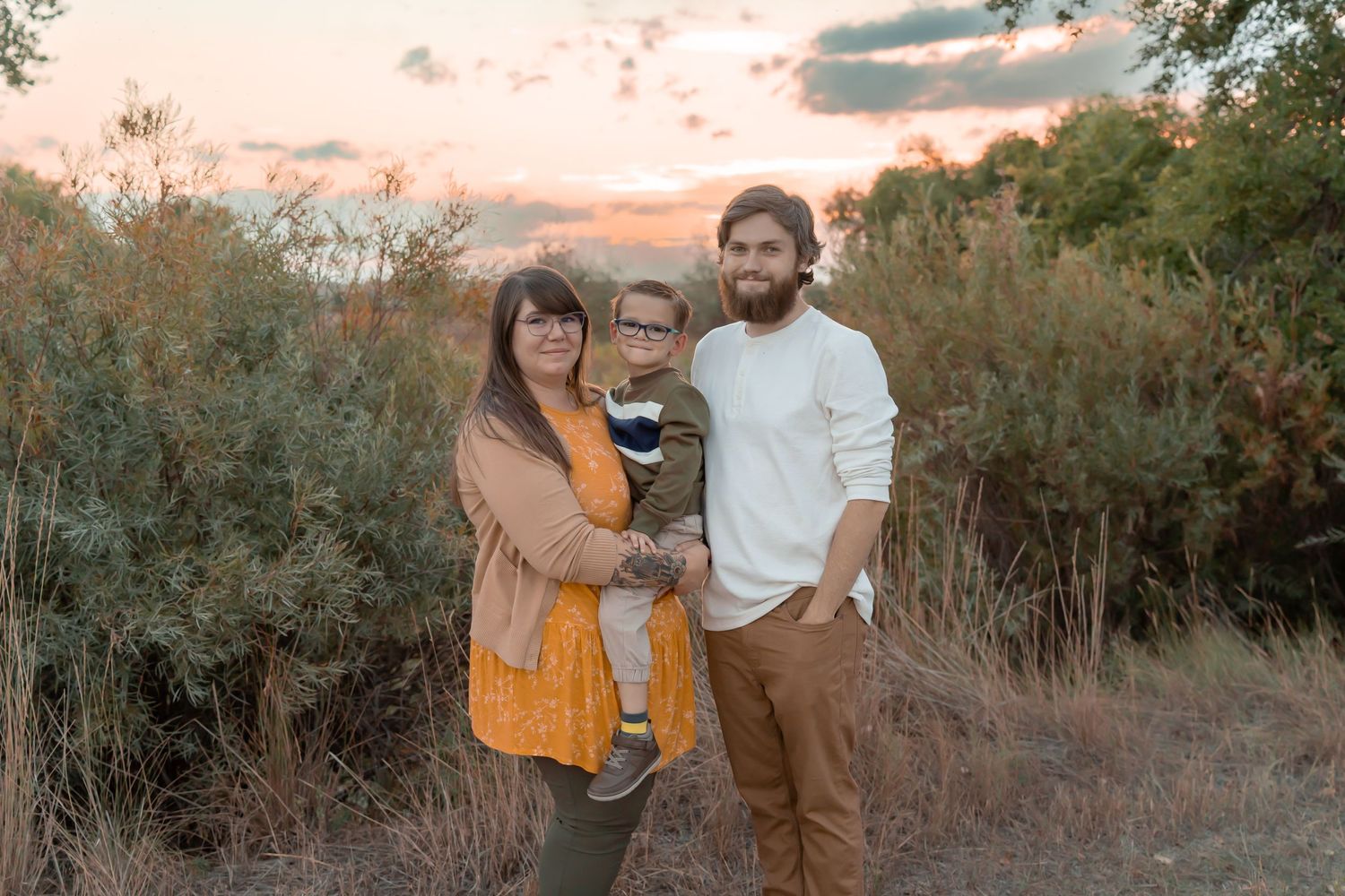 Family group poses together during golden hour in natural outdoor setting.