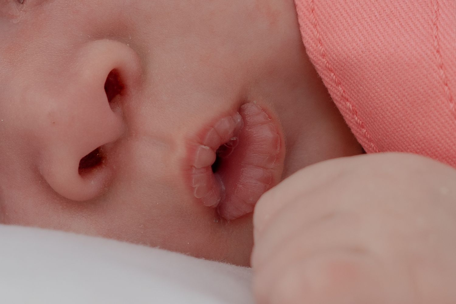 Close detail of sleeping baby with soft pink tones and gentle lighting.