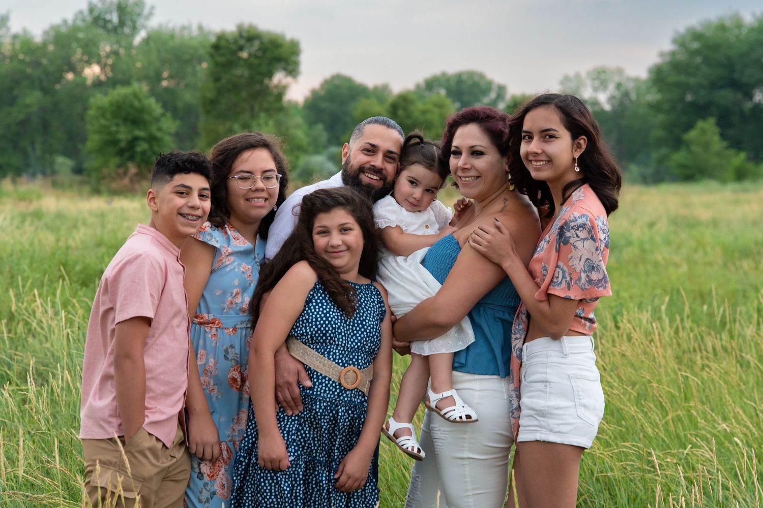 Candid group photos of loved ones laughing and embracing while posing together in a sunny grassy meadow.