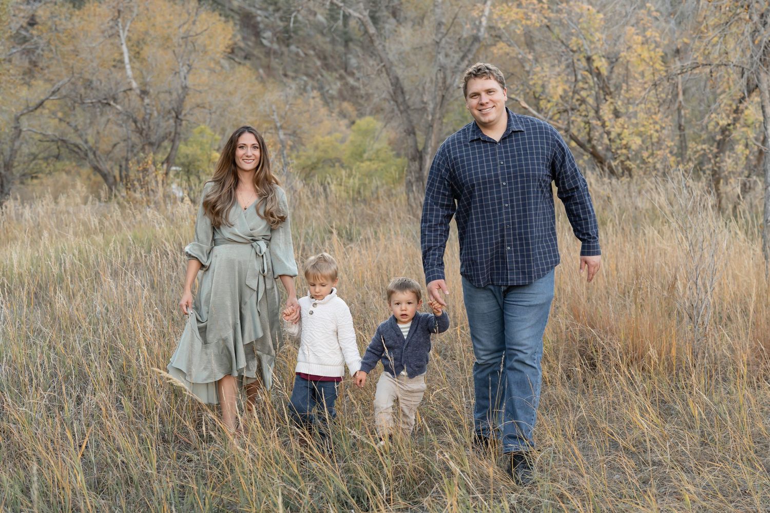 A series of outdoor family portraits taken in a rustic field with tall brown grass and autumn foliage.
