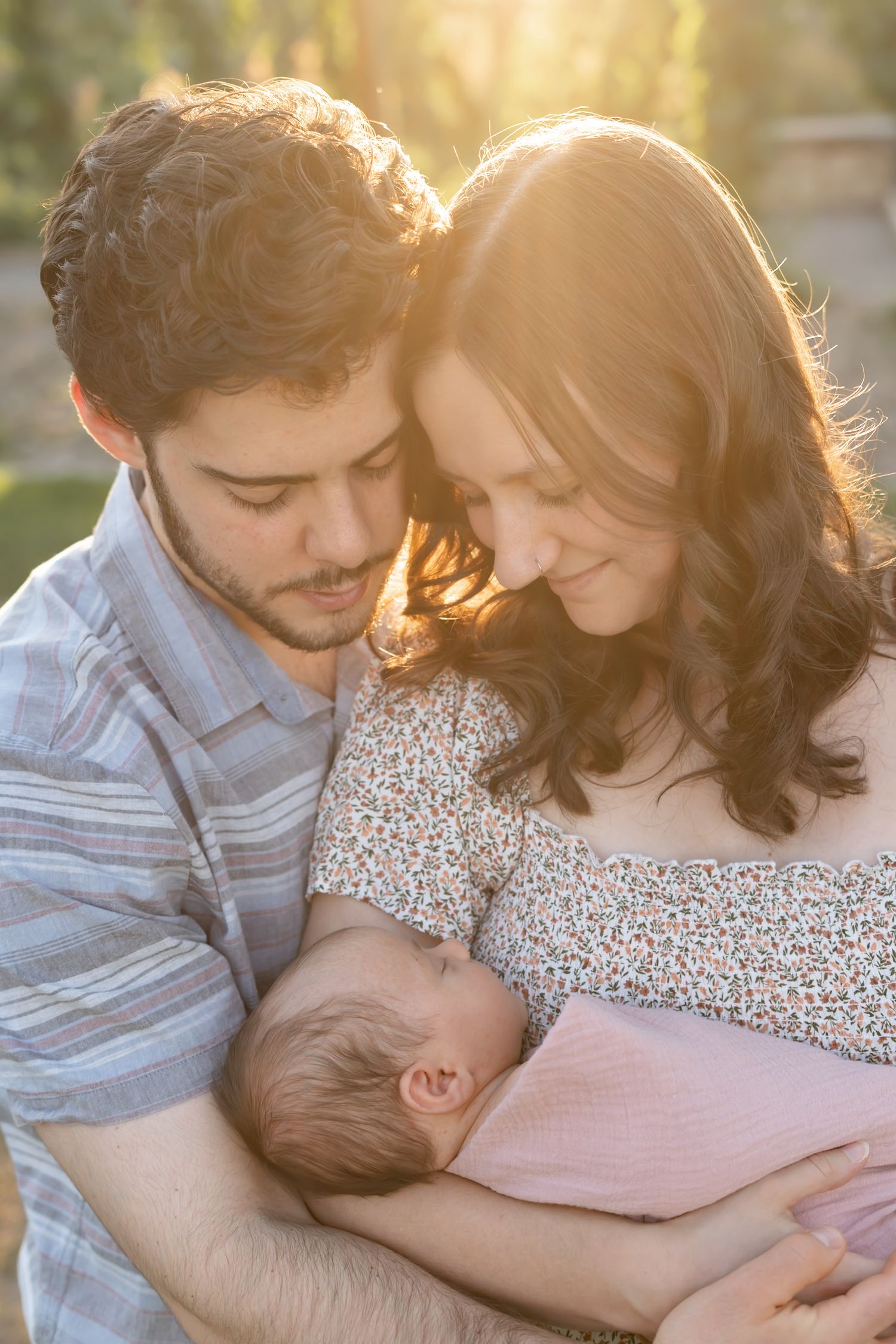 A couple shares an intimate embrace while basking in warm golden sunlight during a romantic outdoor photo session.
