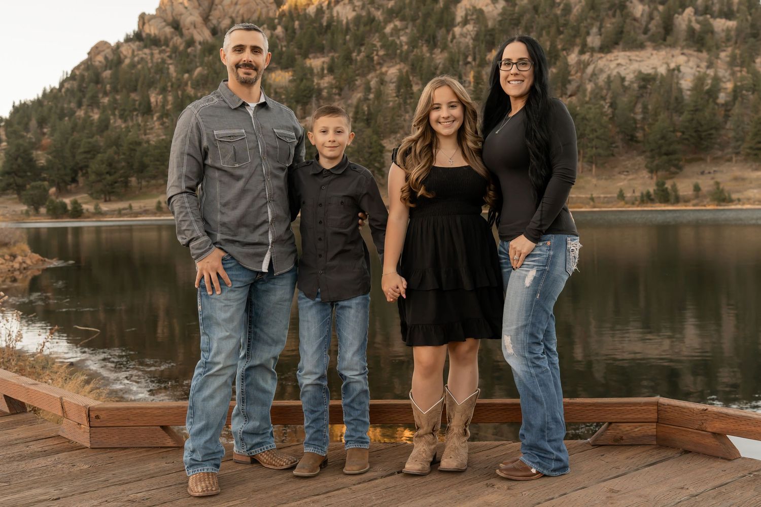 A group poses for outdoor family portraits by a serene mountain lake at sunset.