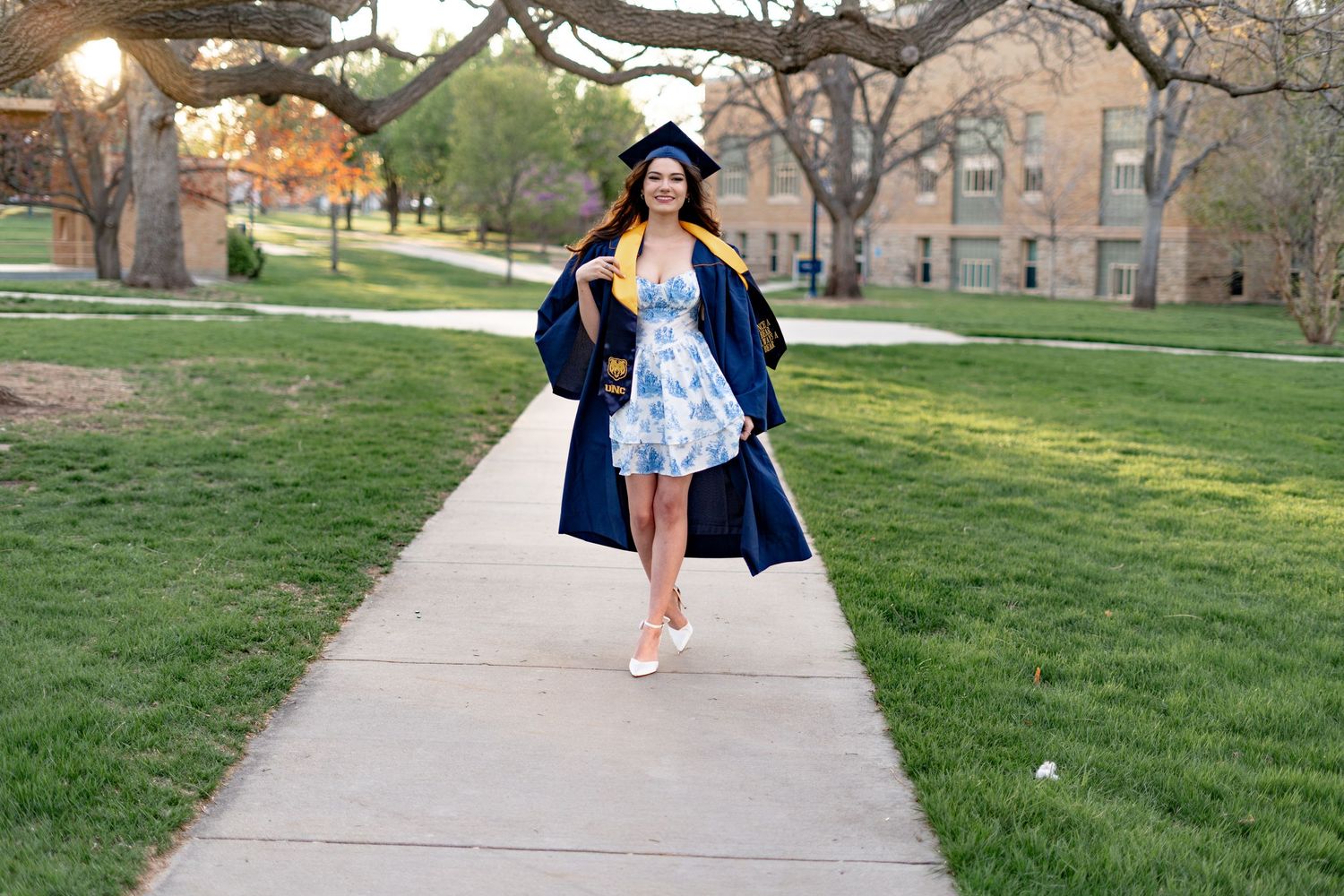 Walking paths and green lawn surround collegiate building with classical architecture.