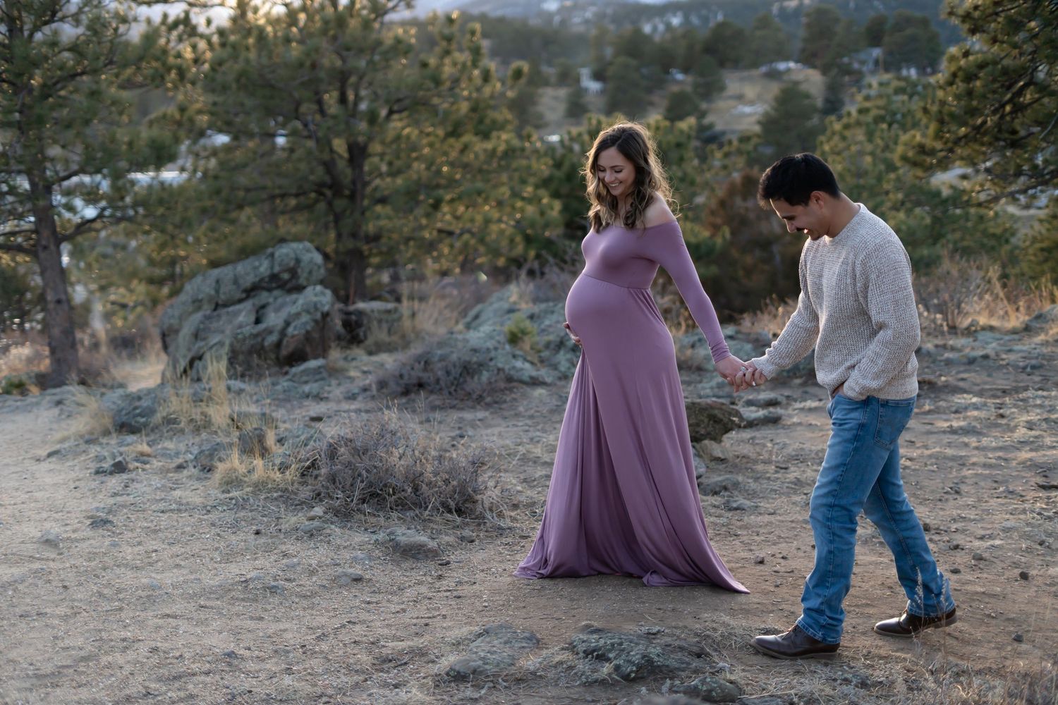 Couple shares tender moment on rocky terrain at sunset.