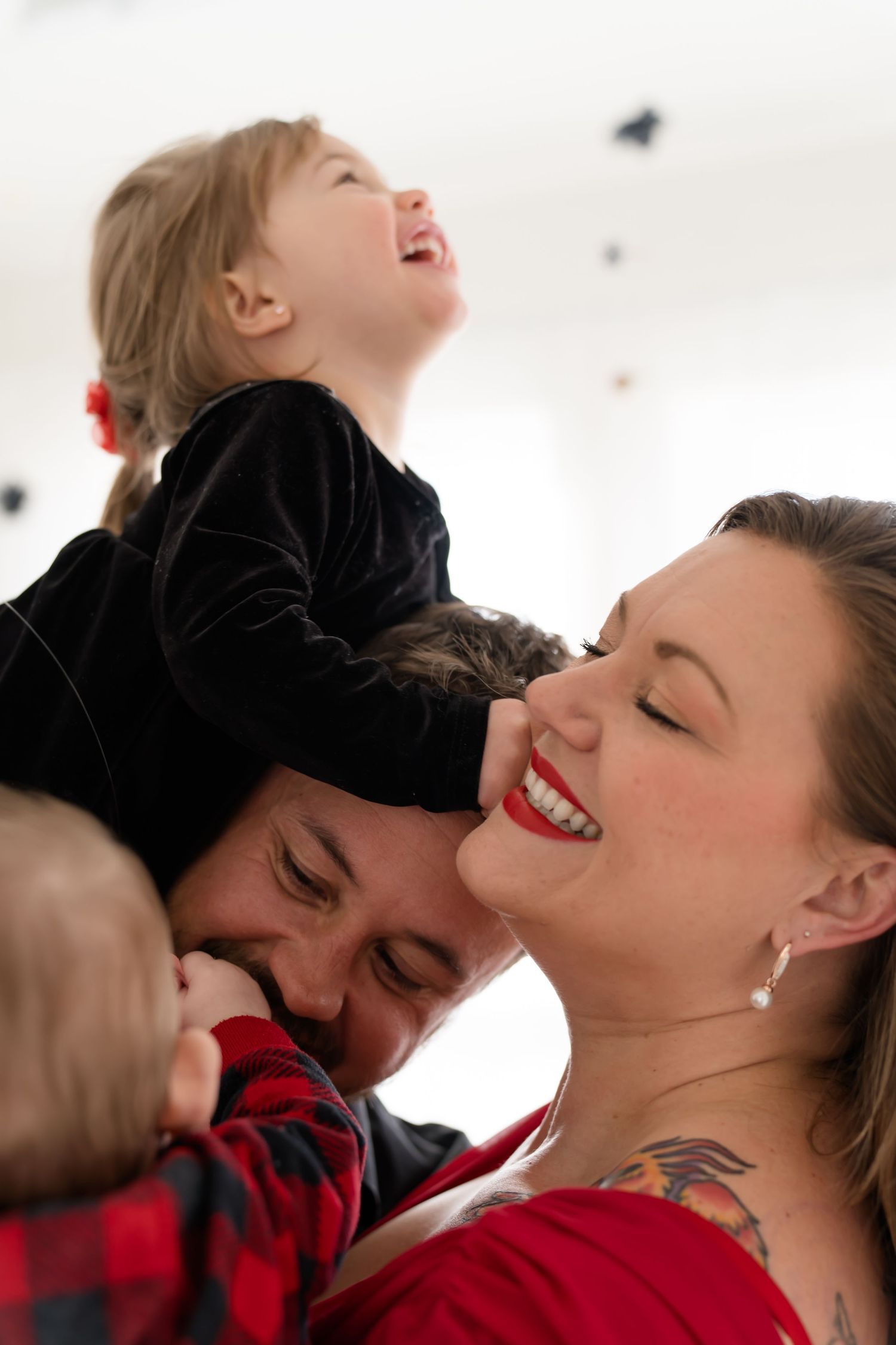 Couple in red and black sharing intimate moments against white backdrop with confetti.