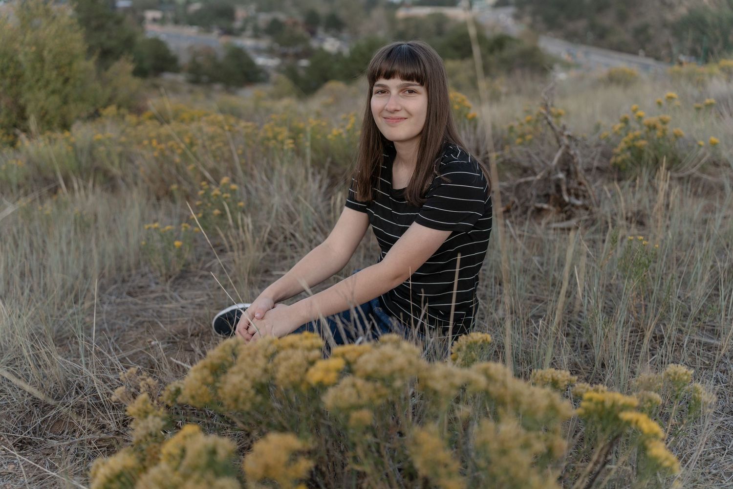 Portrait in desert landscape with yellow wildflowers and brush.