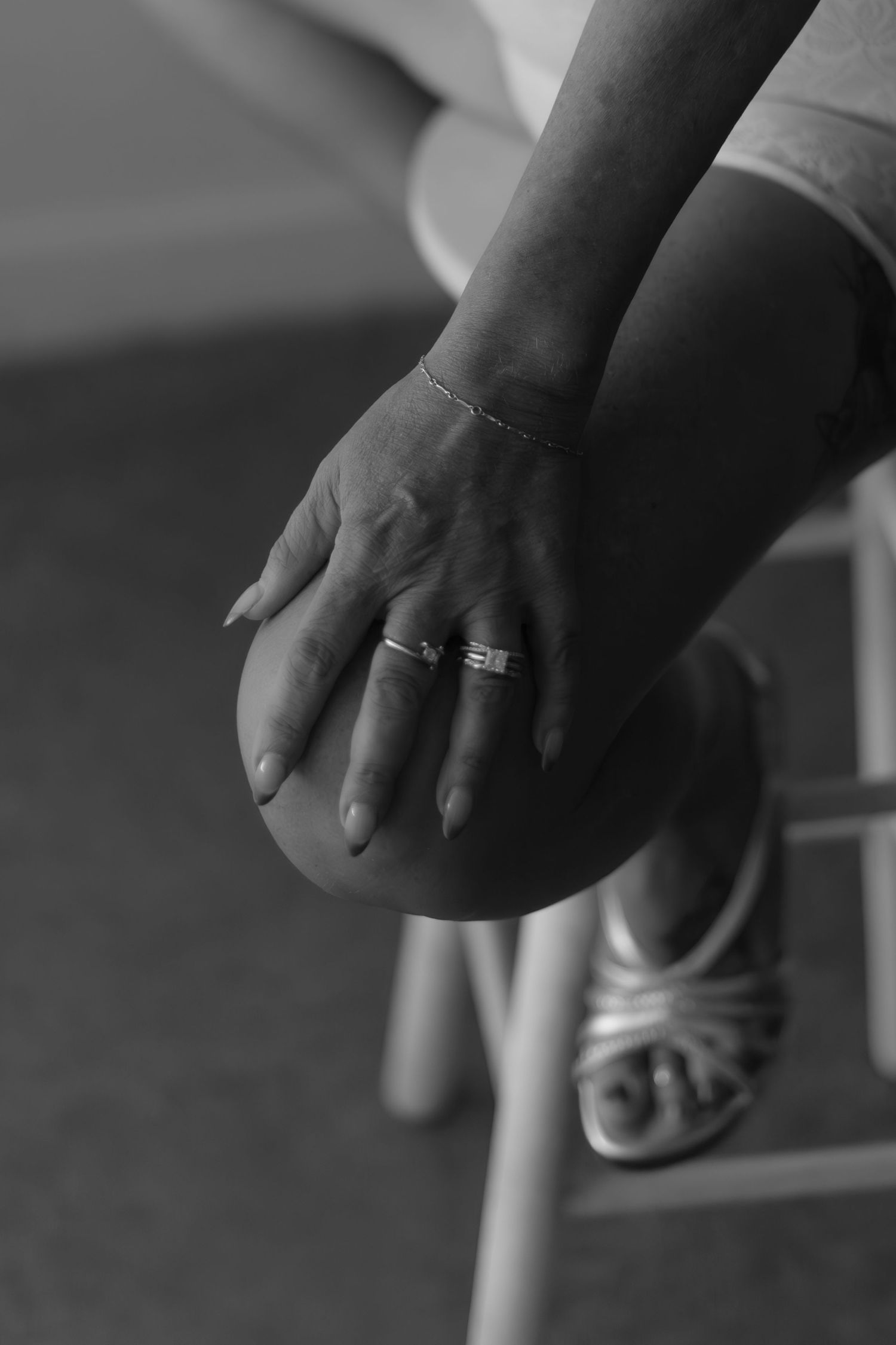Black and white close-up of a hand wearing an engagement ring.