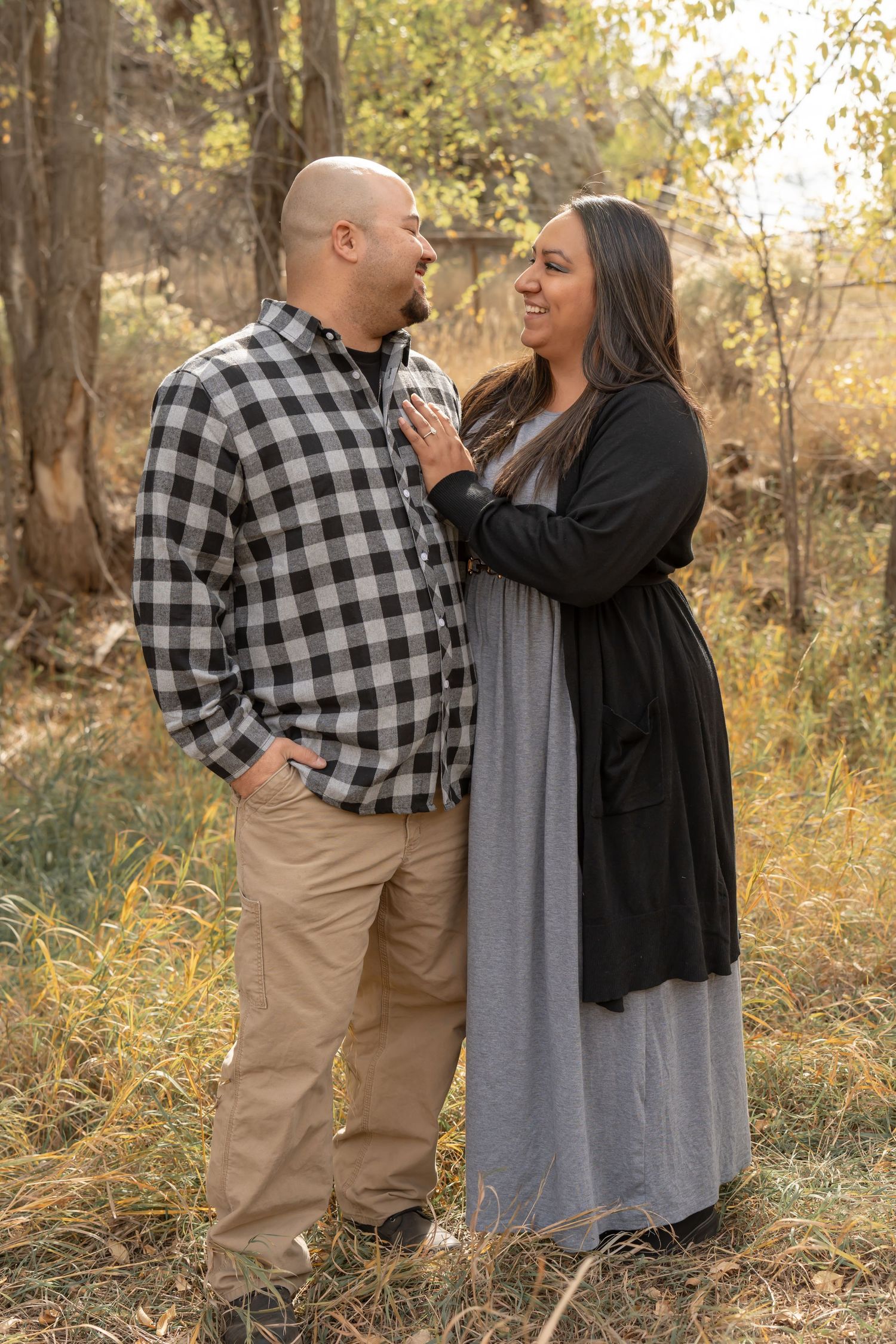 A couple in matching plaid and casual wear sharing a tender moment outdoors.