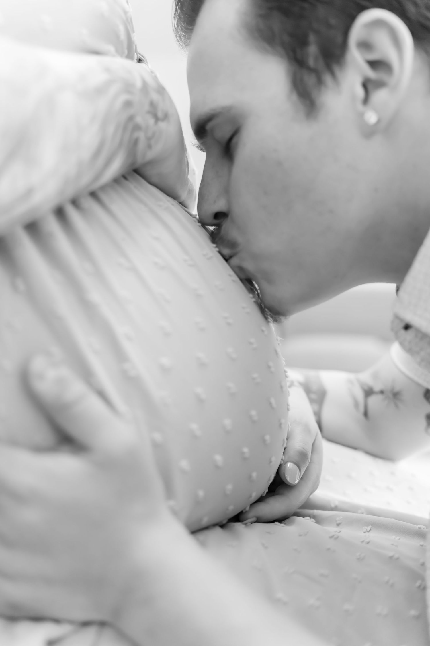 Intimate black and white portrait of tender moments between parent and newborn.