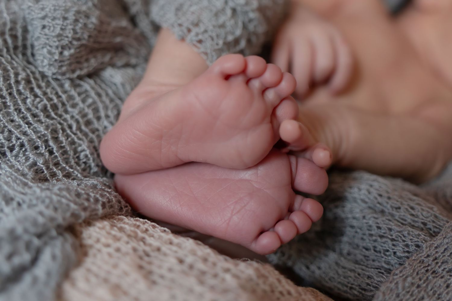 Close up detail shots of newborn baby's tiny feet and toes on knit blanket.
