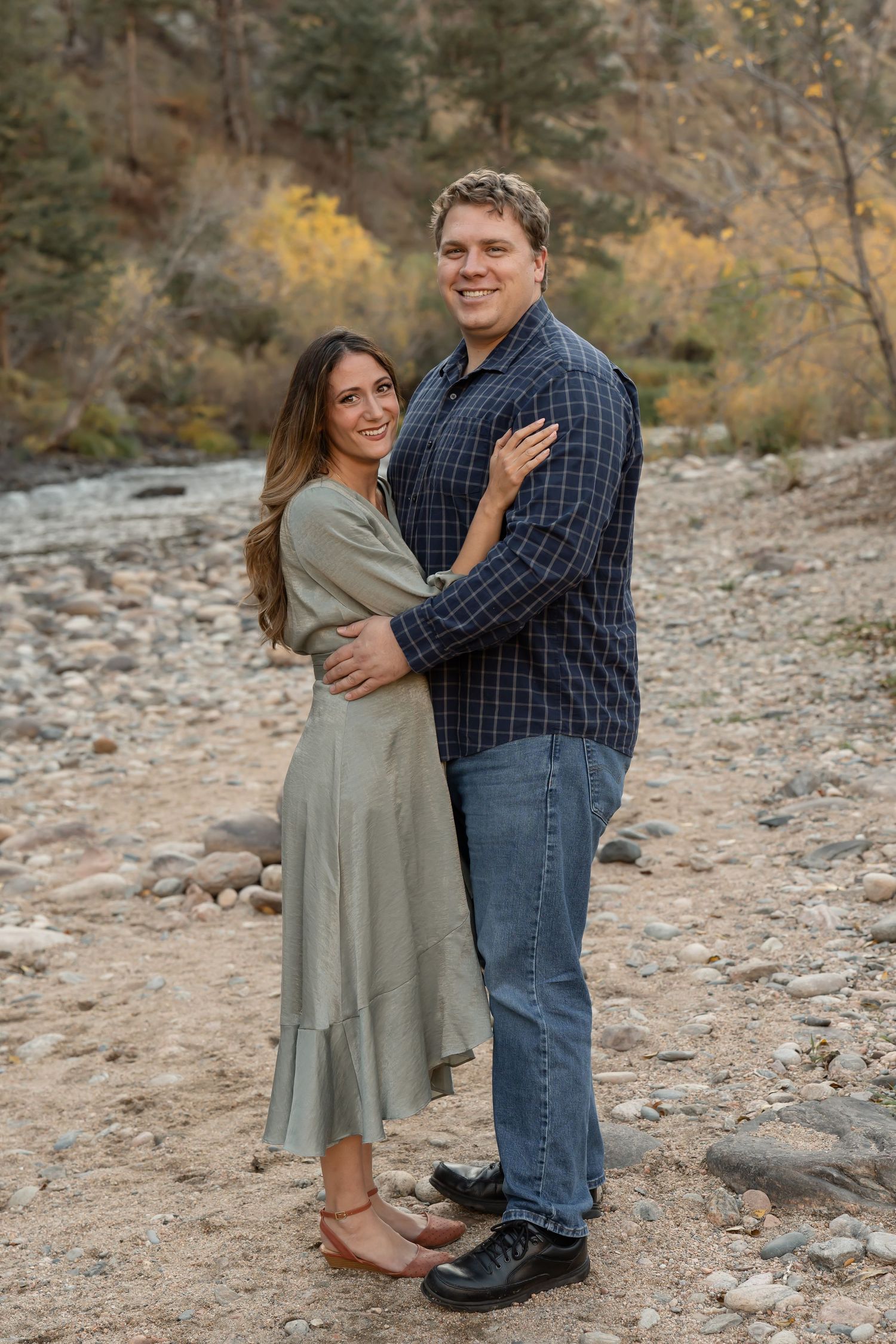 A couple shares a romantic moment together on rocky terrain during an outdoor photo session in autumn.