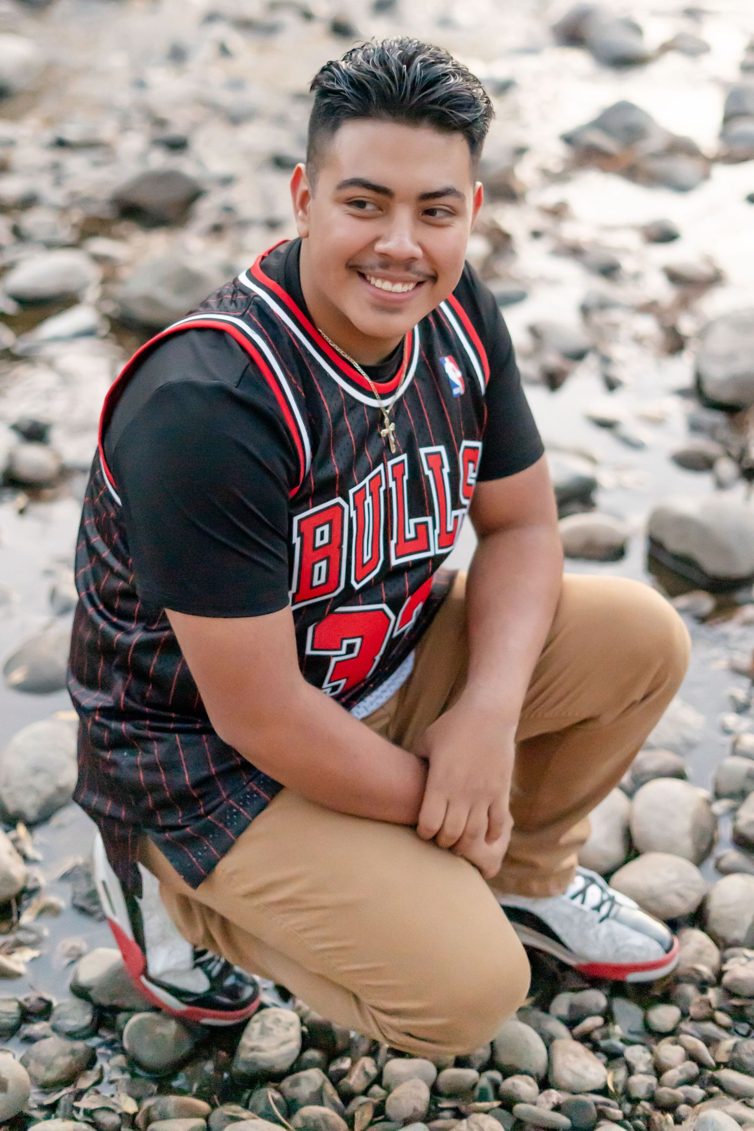 Student in Bulls basketball jersey and khaki pants poses on rocky terrain.