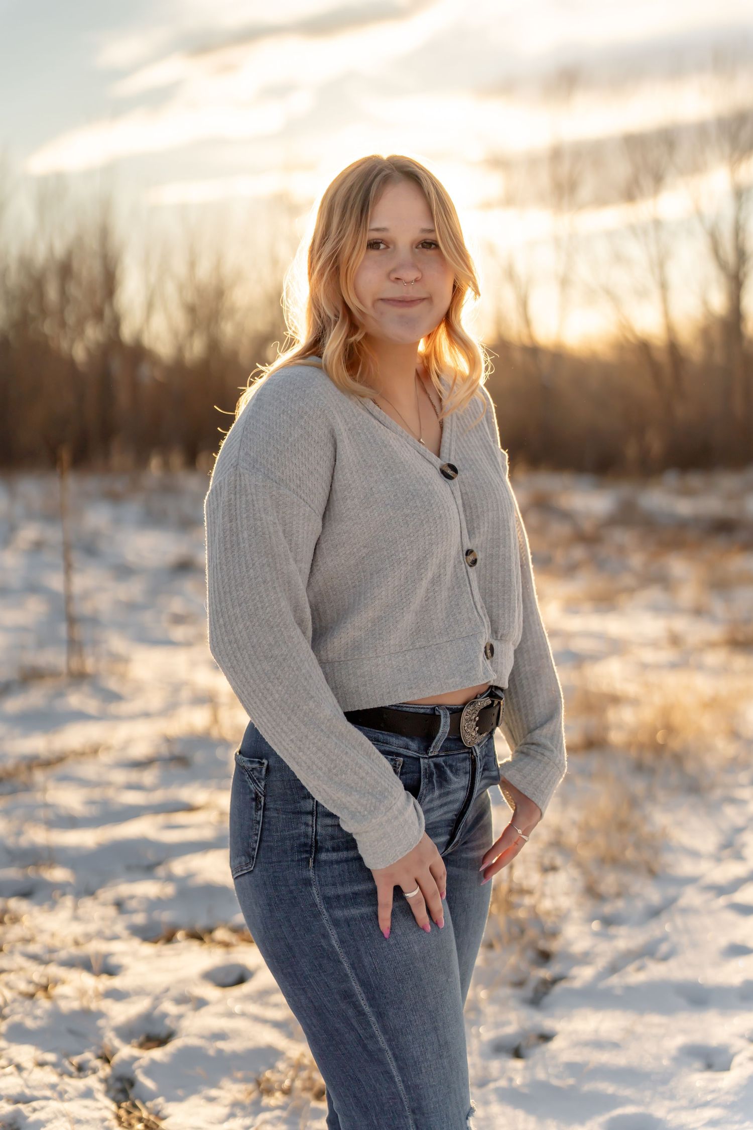 Winter portrait of person in gray cardigan and jeans during golden hour.