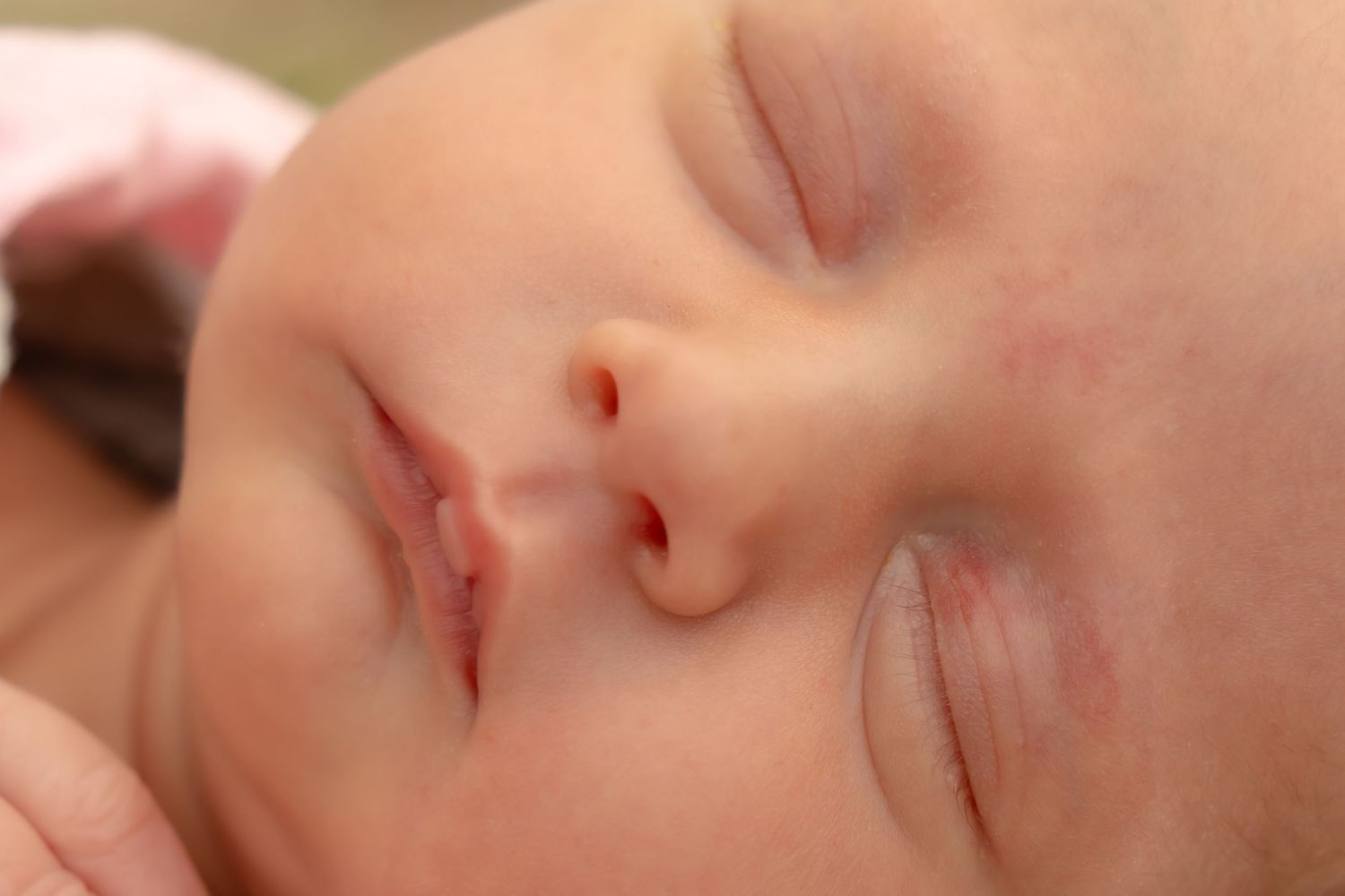 Close-up portrait of a sleeping baby's serene face against white background.