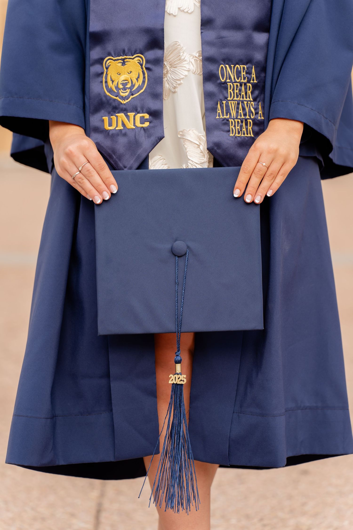 Detail shot of navy blue graduation gowns with UNC logos and tassels.