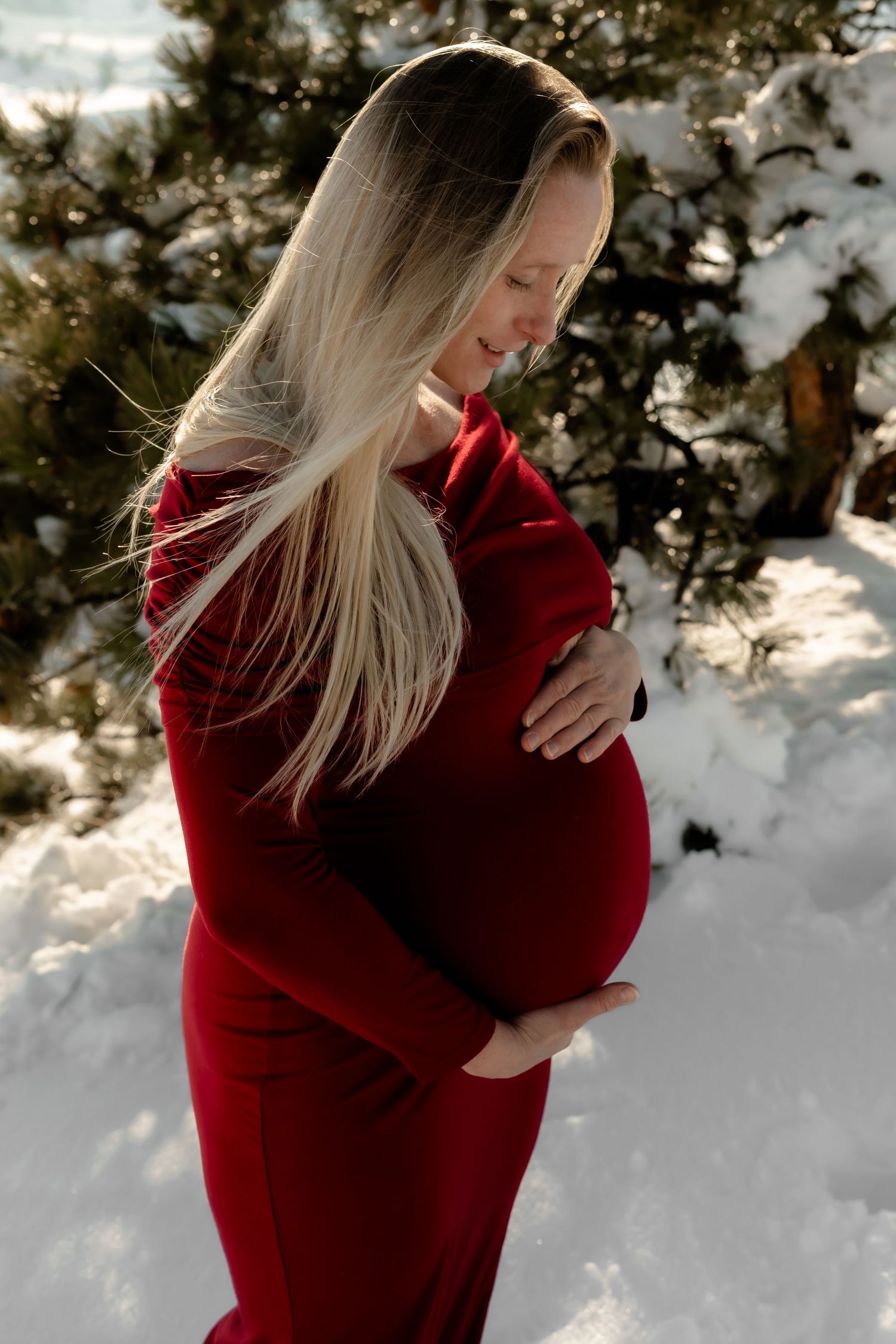 Winter maternity portrait with snowy forest background.