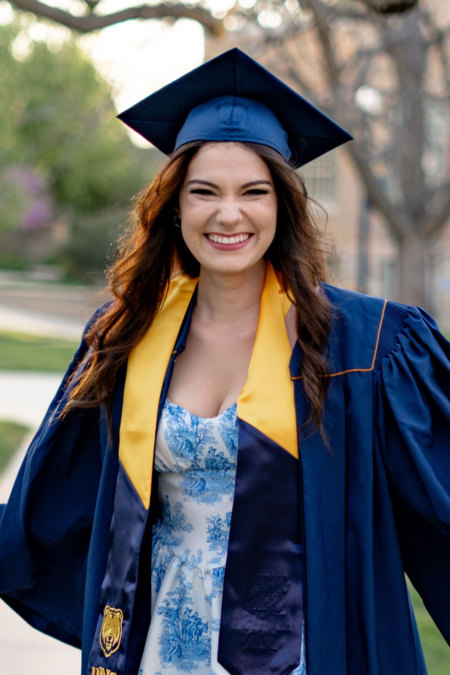 Graduation photos showing someone in a navy cap and gown with gold trim outdoors.