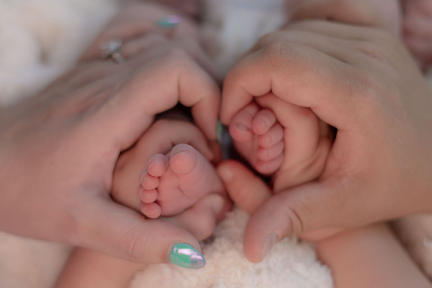 Close-up of tiny newborn feet held in adult hands.