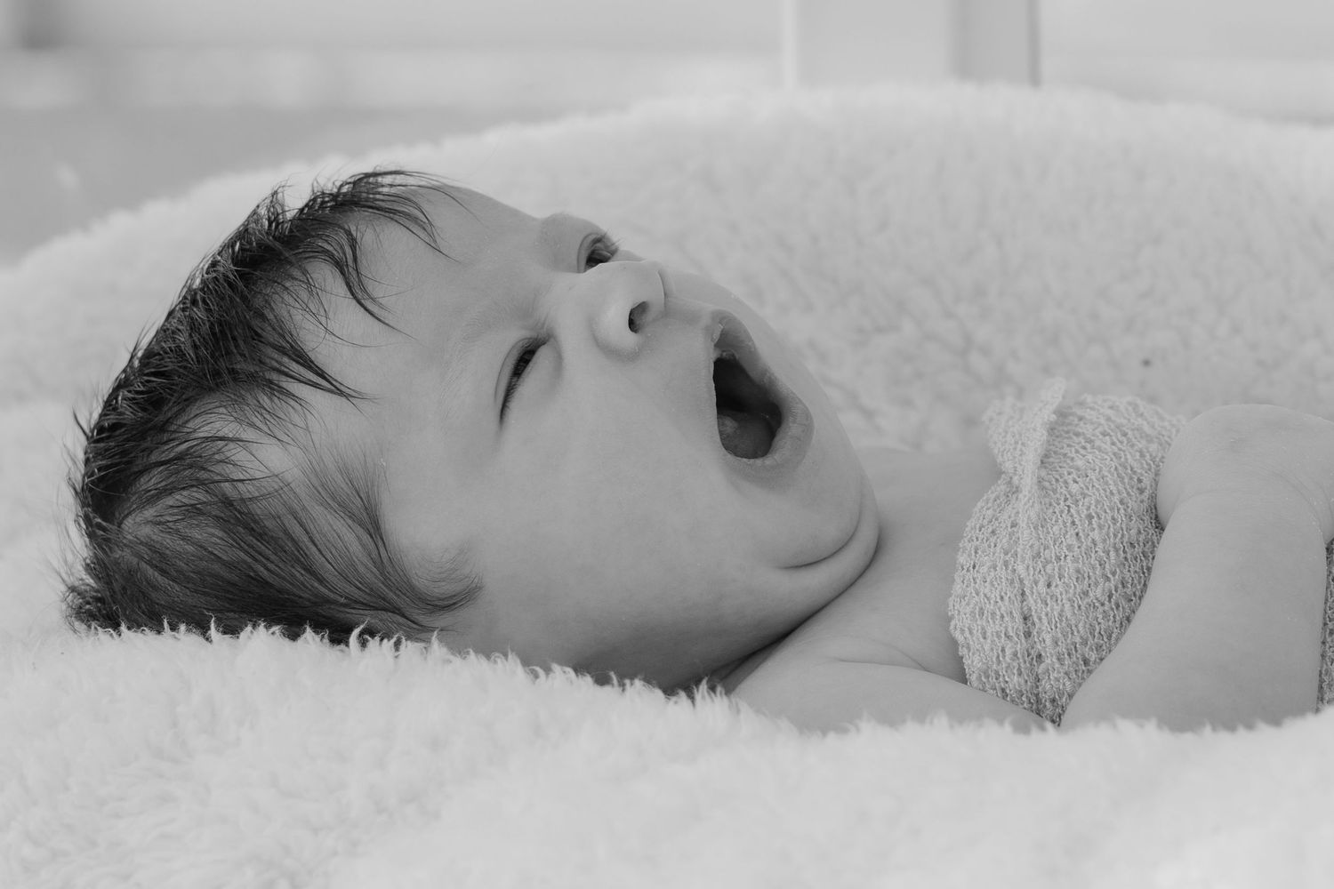 Artistic black and white portrait of sleeping infant on soft textured background.
