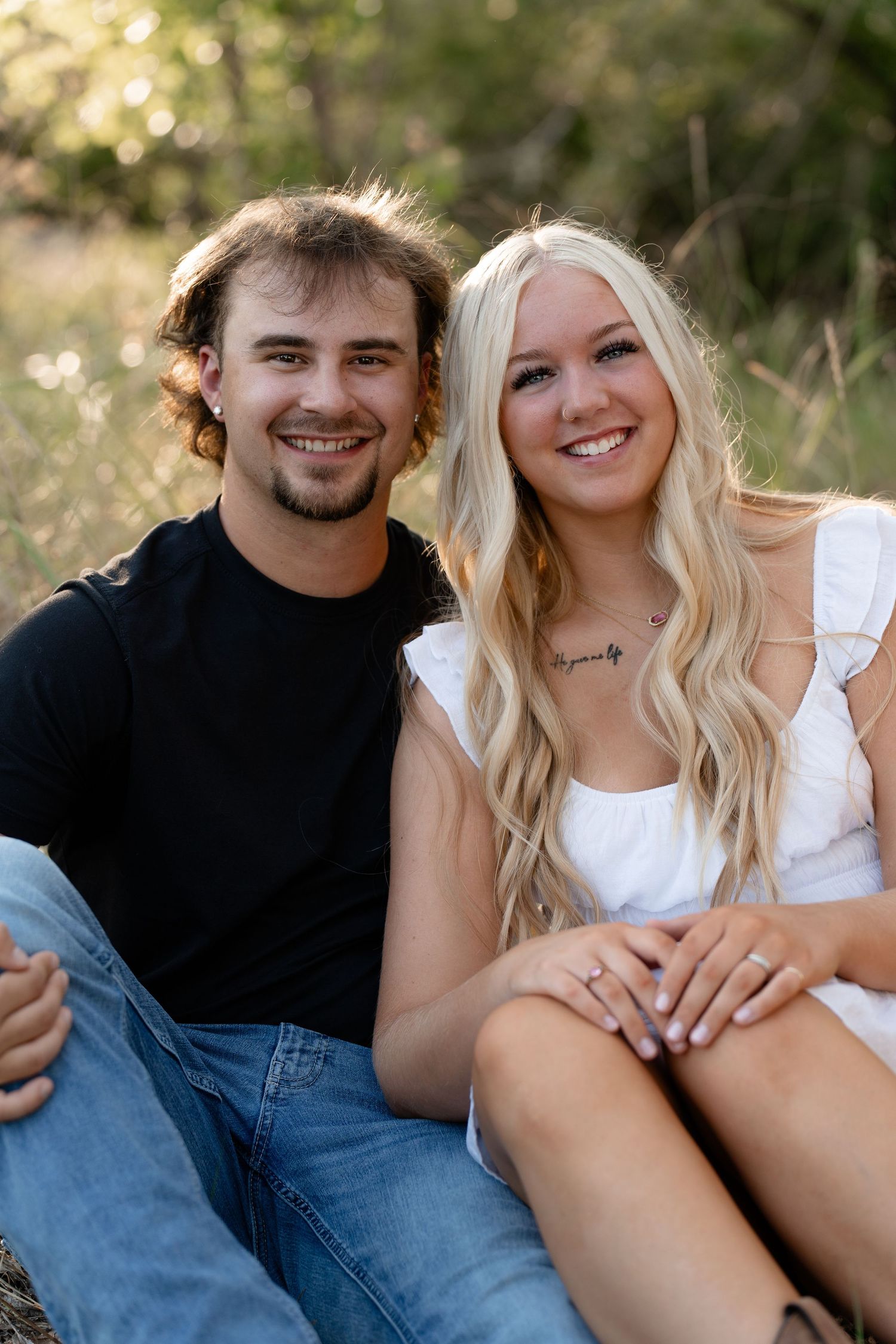 A couple sits together outdoors sharing a relaxed moment in casual clothing.