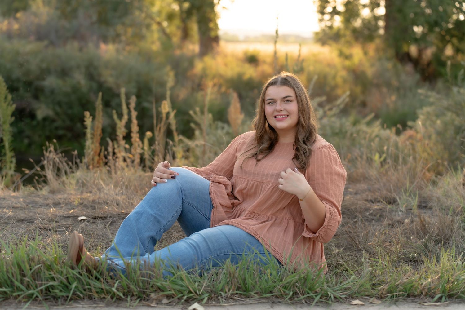 Professional senior graduation photoshoot in a rustic outdoor setting at golden hour sunset.