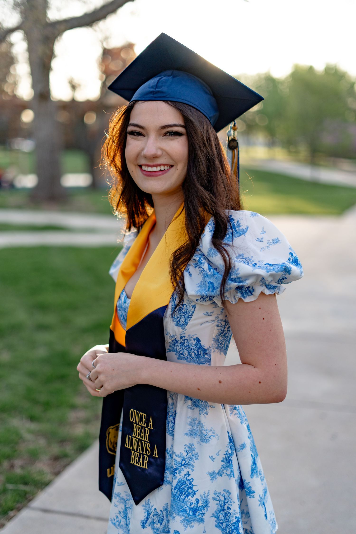 Candid graduation photos showing someone in blue and white floral dress with academic regalia.