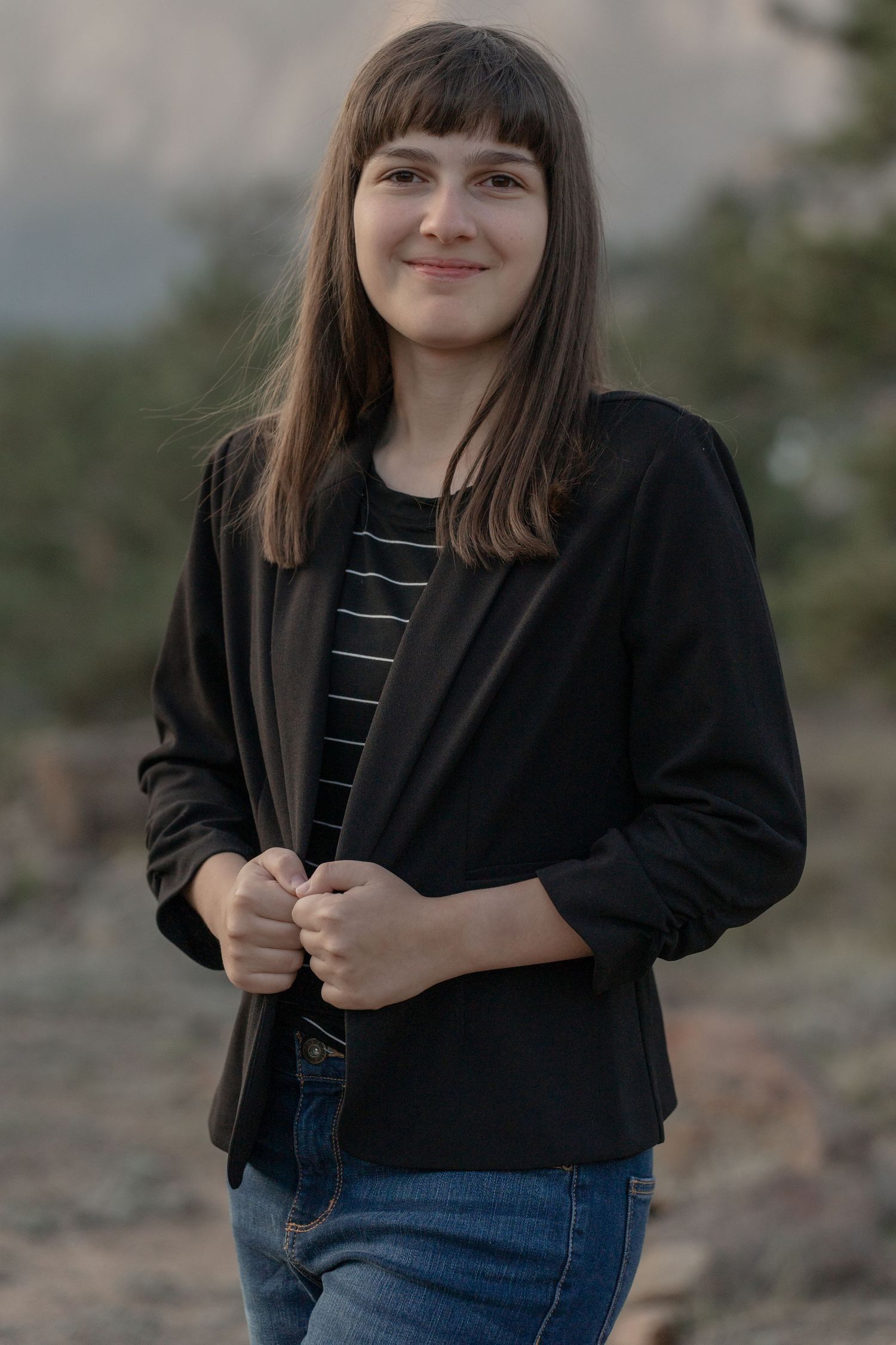 A casual portrait outdoors wearing a black cardigan and striped shirt.