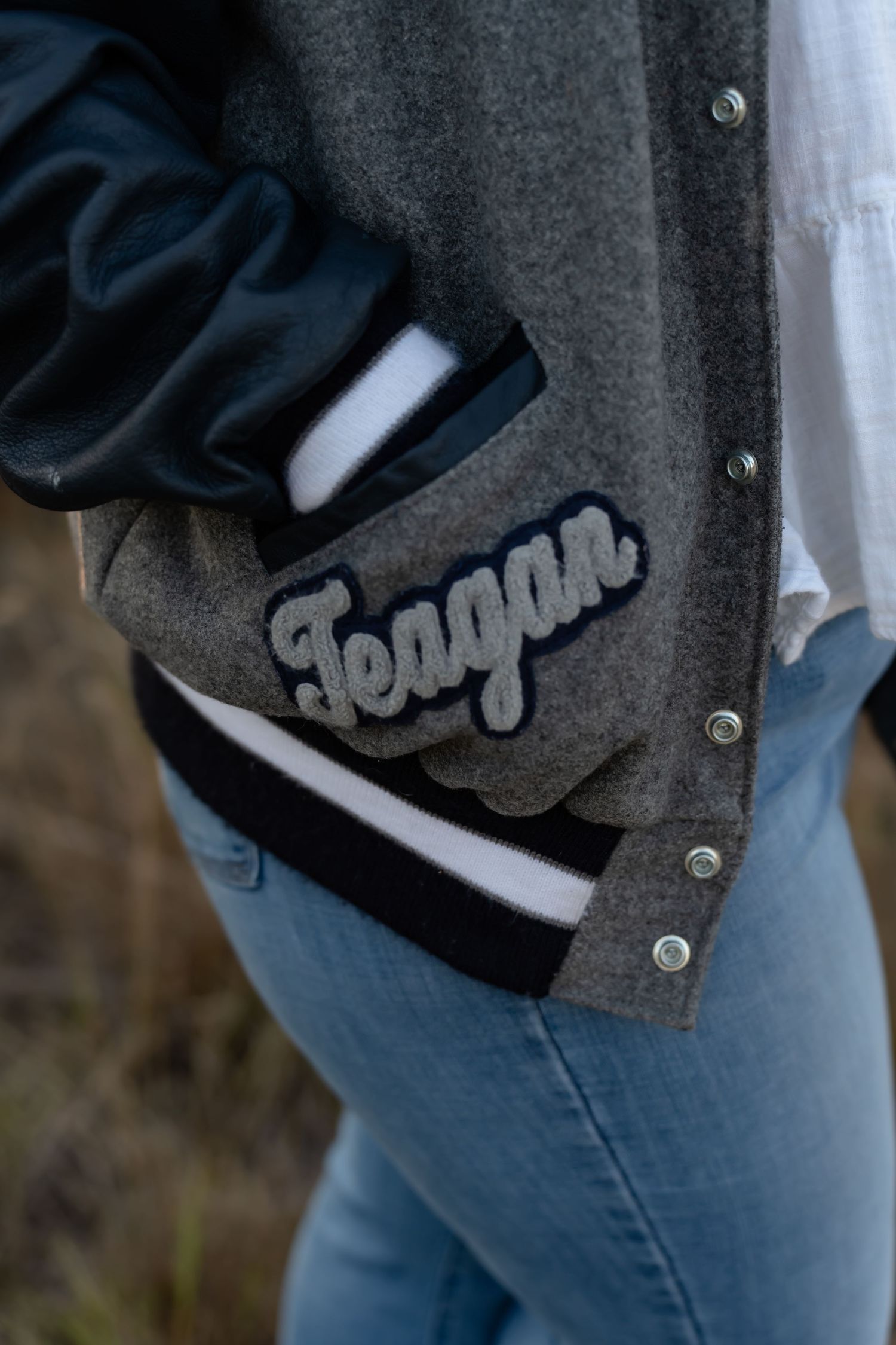 Close-up details of a varsity letterman jacket showing gray and navy design elements.