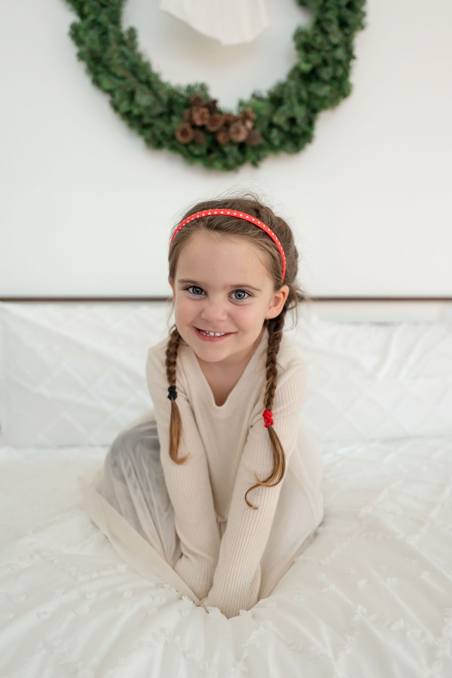 A series of holiday portraits with festive wreaths and a cozy beige sweater against a white background.