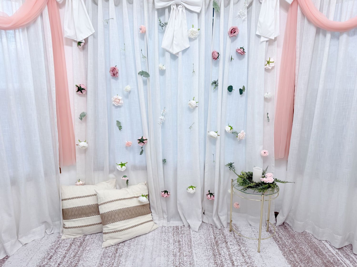 White curtains with pink accents and star decorations create a whimsical backdrop for a photo booth or party setting.