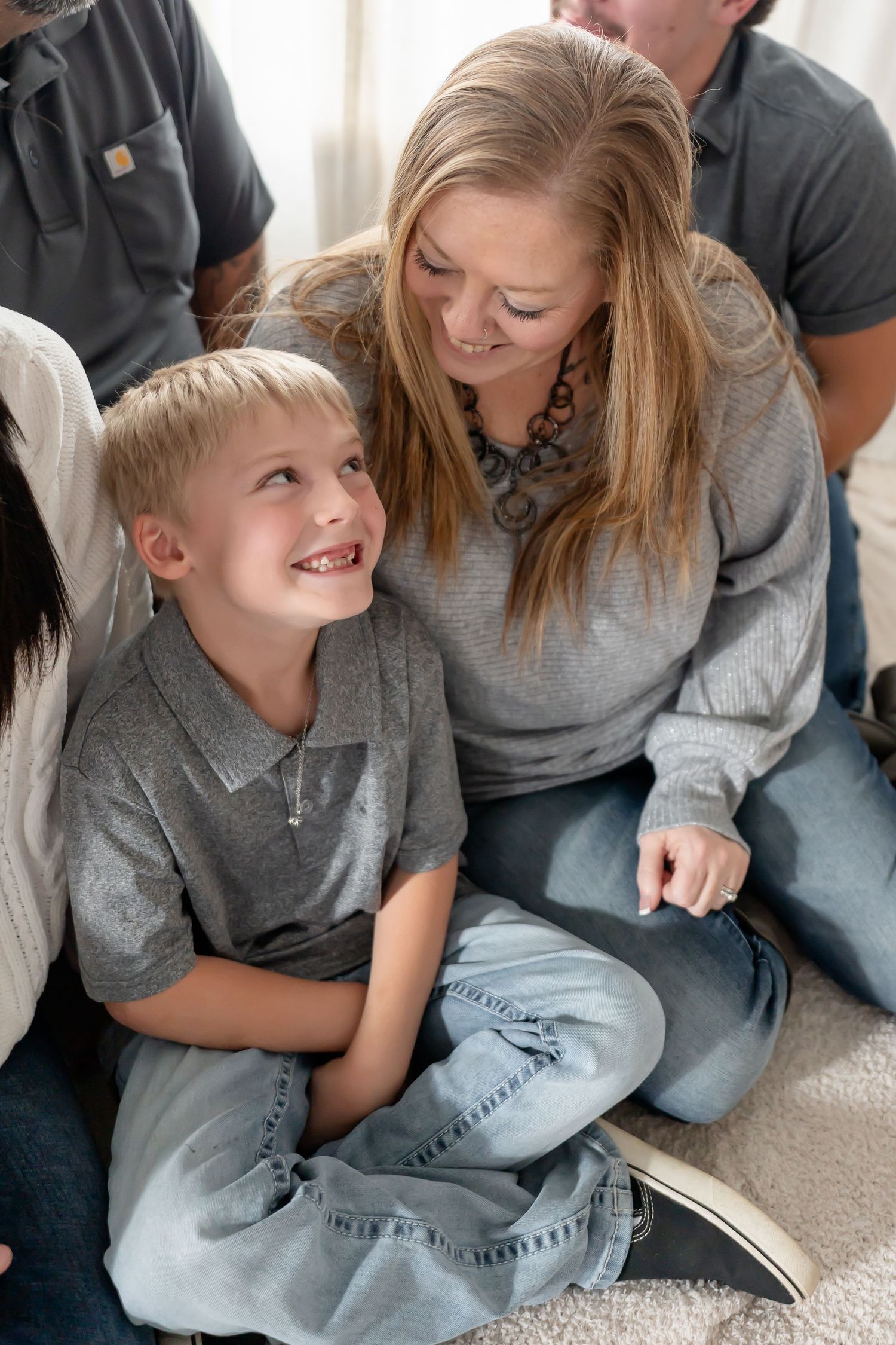 A series of candid moments showing a parent and child sharing playful interactions while sitting on a light carpet.