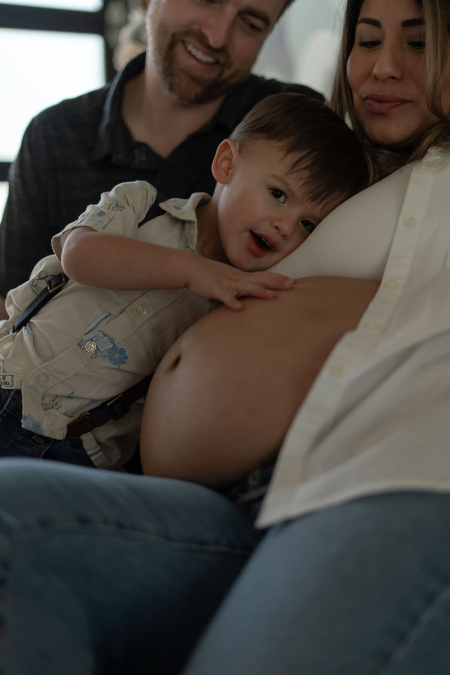 Intimate family moment with toddler resting head on pregnant belly.