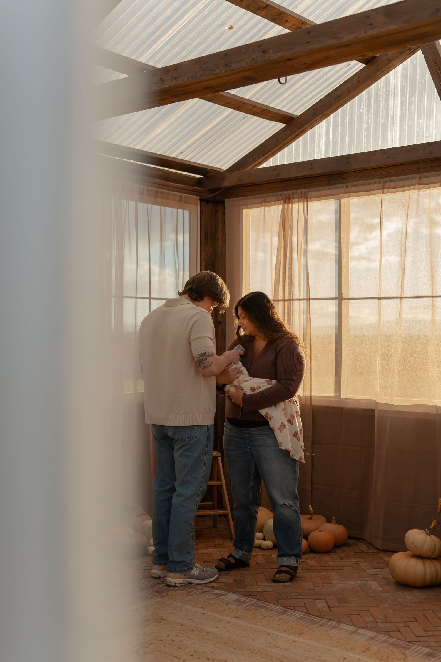 Two people working together in a rustic sunroom with wooden beams and pumpkins on the floor.