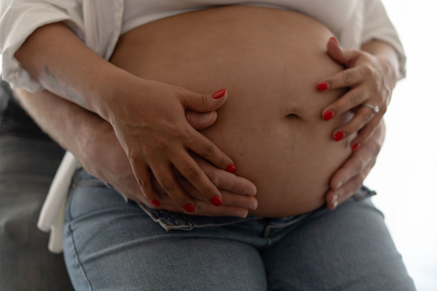 Hands cradling pregnant belly shown from different angles during maternity photoshoot.